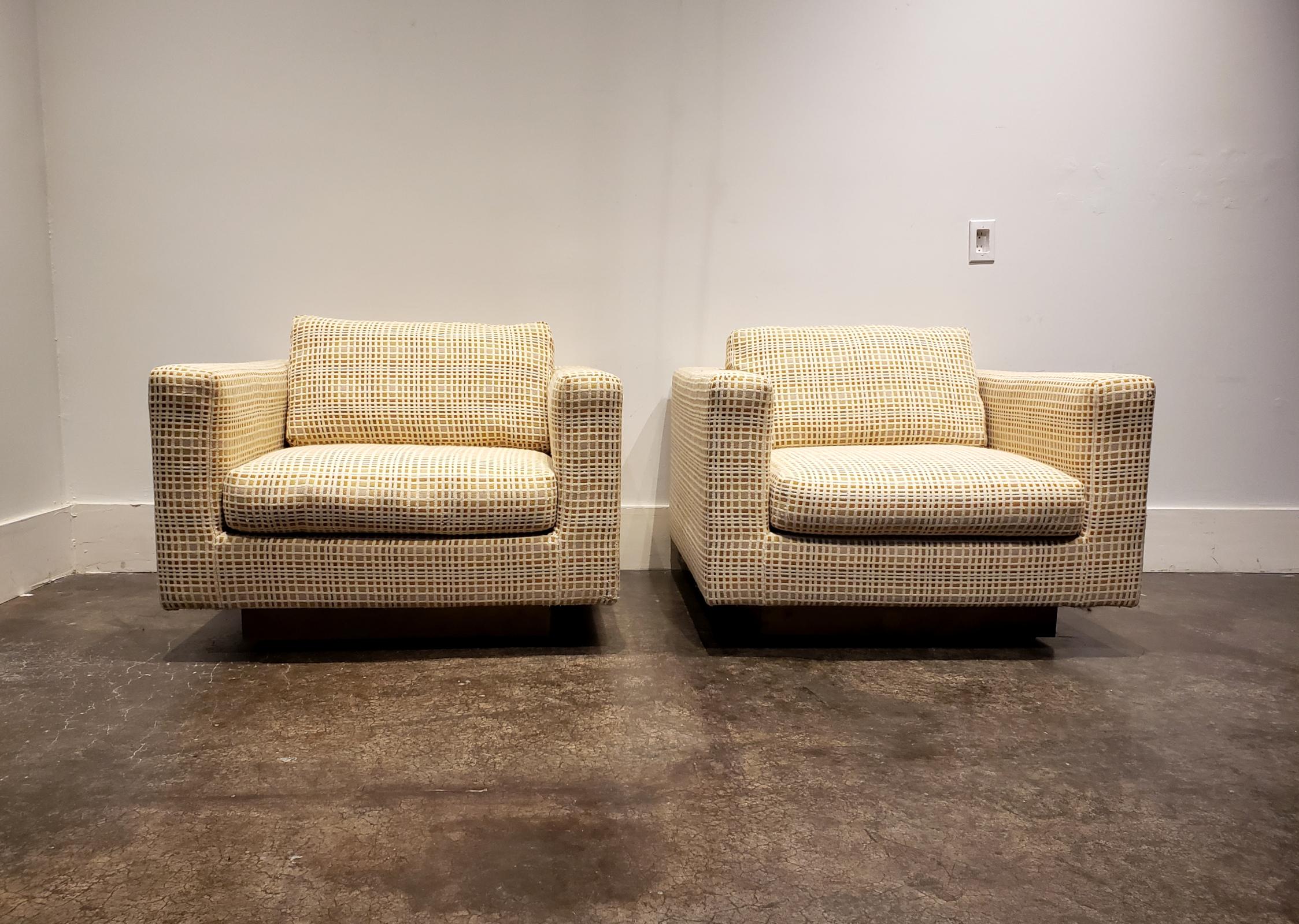 A pair of large and imposing Dunbar club chairs. Original checkered upholstery attributed to Jack Lenor Larsen. Square pedestal base finished in brass veneer. Chairs are sturdy and look great as is or would make a great canvas for an exciting re