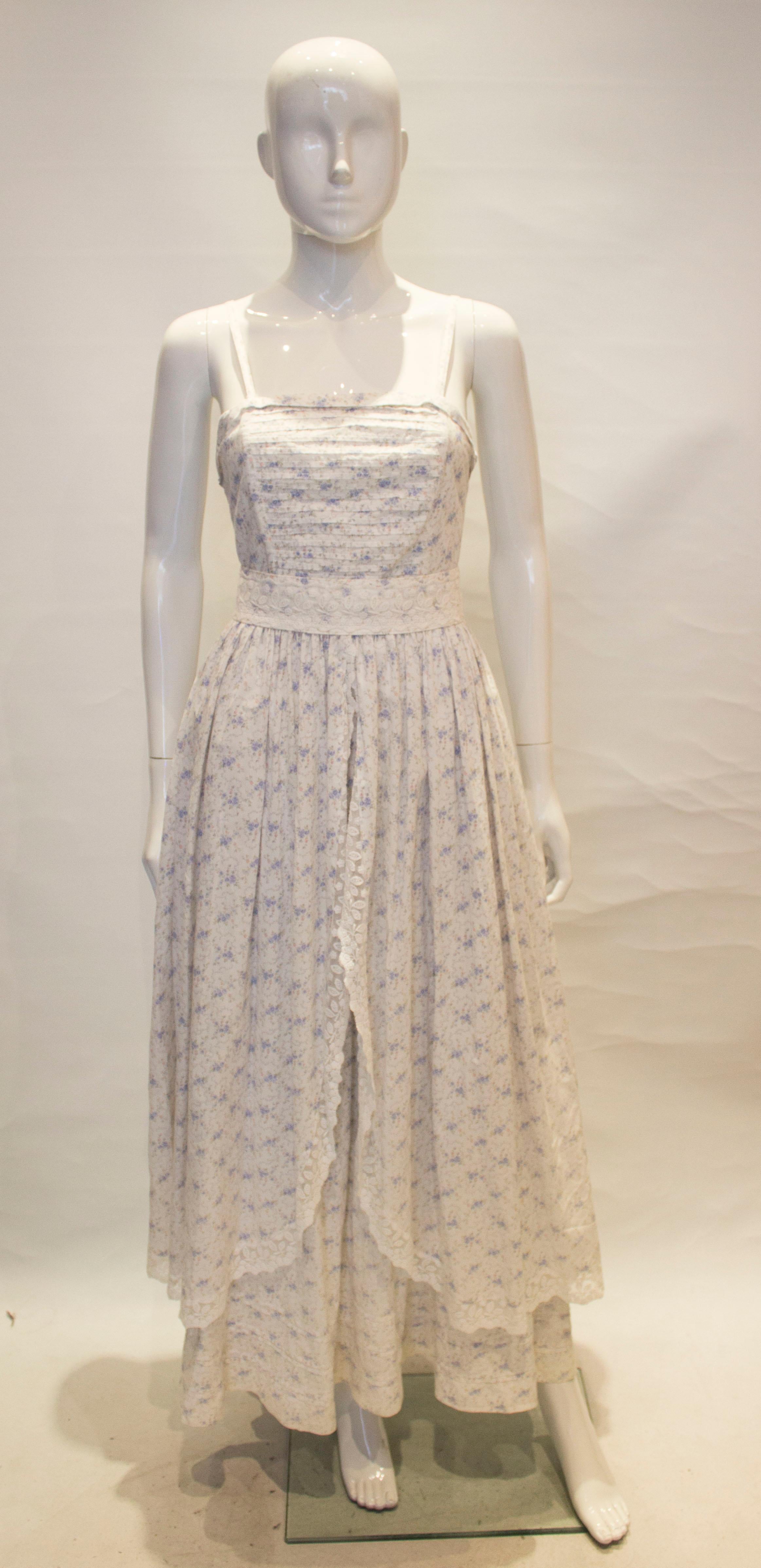 An interesting  , Laura Ashley dress and  matching bolero. The dress has a white background with floral print , central back zip, and visible underskirt. with lace detail.
Measurements: dress bust 35'', waist 26'',length 59''  jacket 36'' length