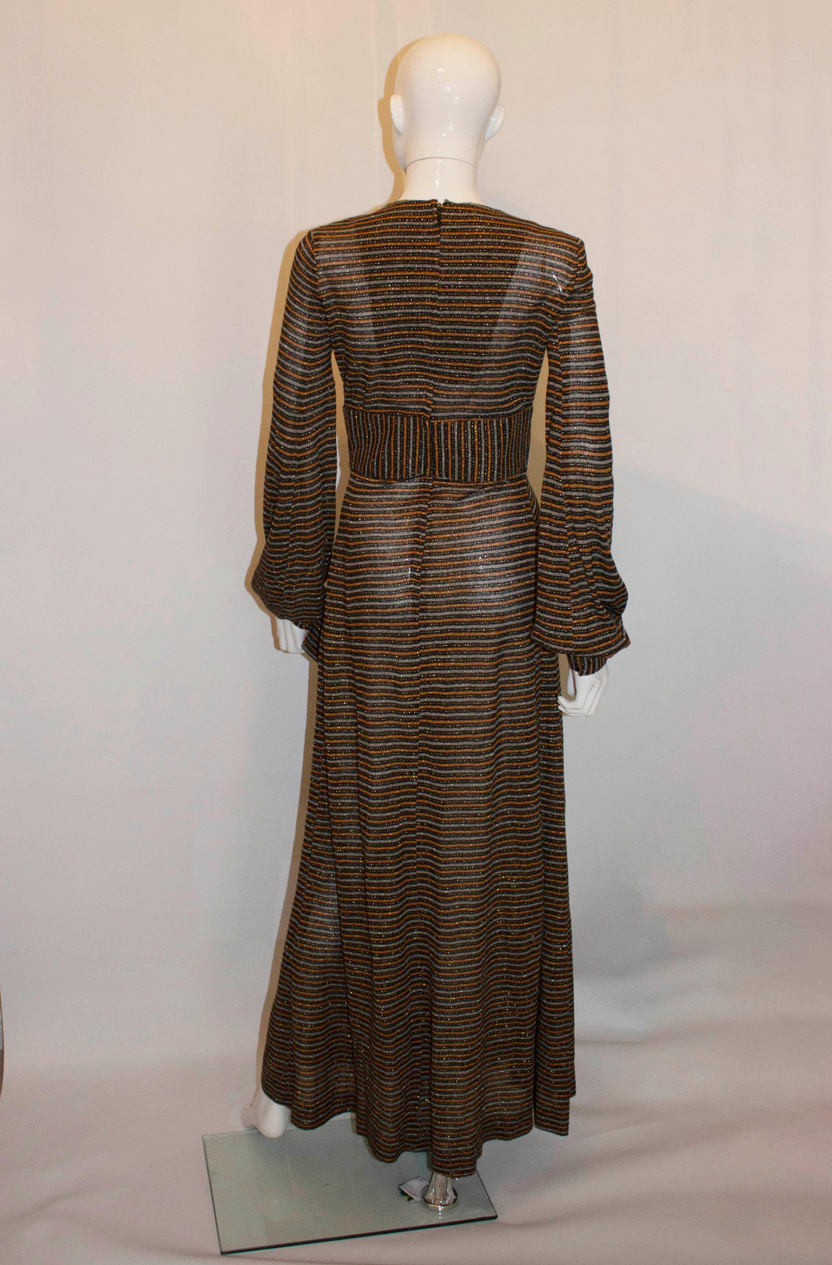 A head turning vintage gown by Laura Lee London.  In a mix of grey ,brown and black stripe with gold running through, the dress has a v neckline. gold detail and pleats at the front , a central back zip and popper cuffs.
Measurements Bust 35'', 
