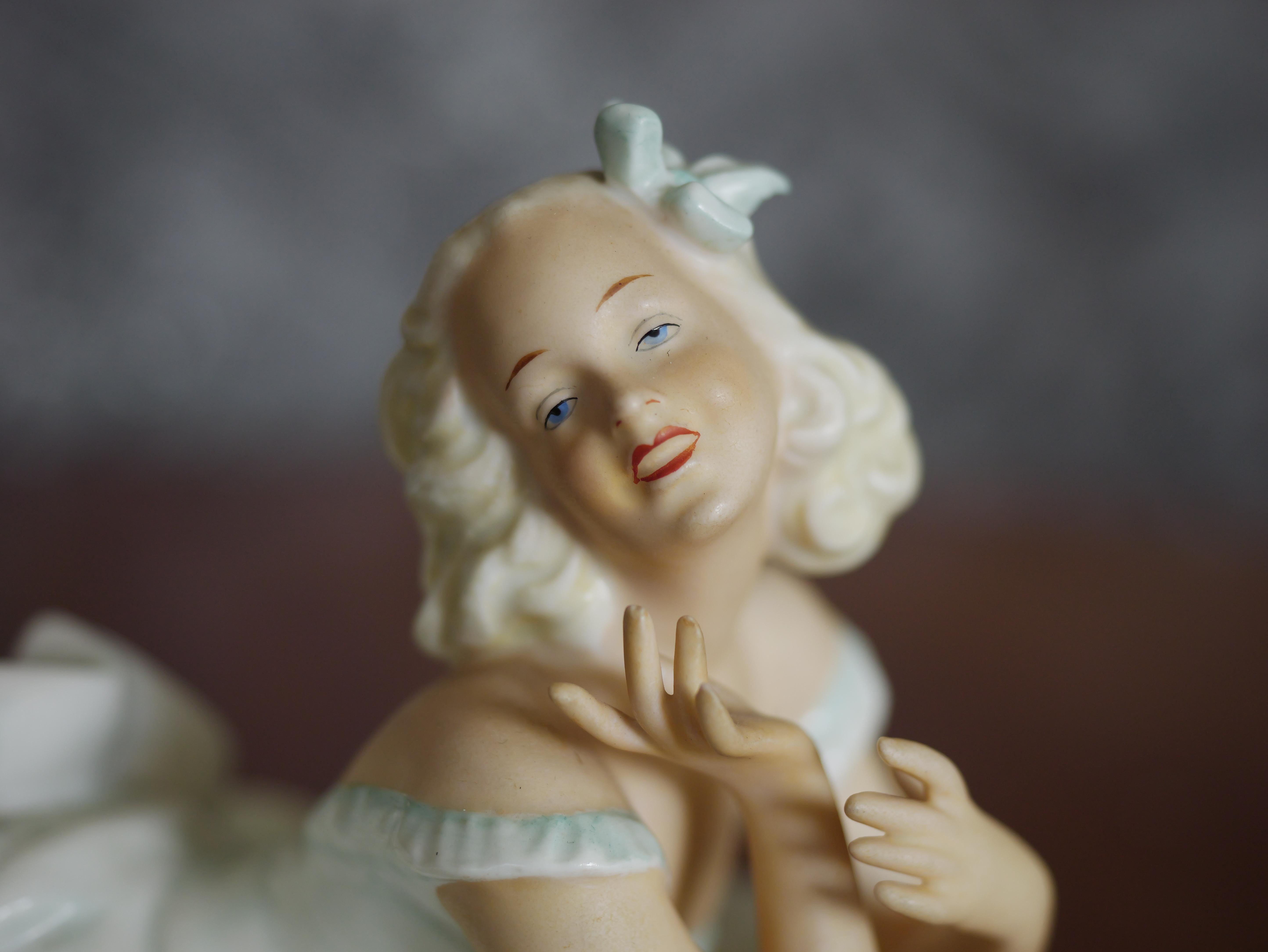 This vintage porcelain figure is a stunning example of Schaubach Kunst craftsmanship from the period between 1945 and 1965. The figure depicts a lady in a graceful reclining pose, elegantly dressed in a flowing white gown. The attention to detail is