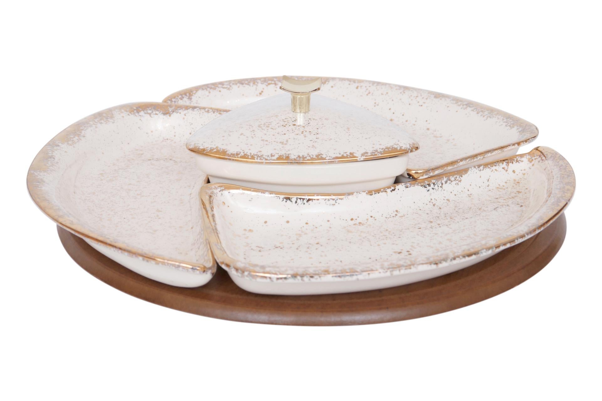 A divided serving dish set with a matching lazy Susan made by Maurice & Co of California. A central triangular bowl and three curved triangular dishes are an off white flecked and edged with gold. The bowl has a lid that lifts with a concave