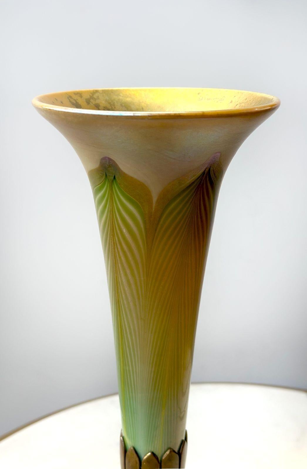 Magnifique vase en verre Favrile à plumes tirées de Tiffany Studios, de forme unique en trompette. Le séduisant verre favrile est composé de tons dorés et verts qui se marient parfaitement avec la base en bronze doré qui soutient gracieusement