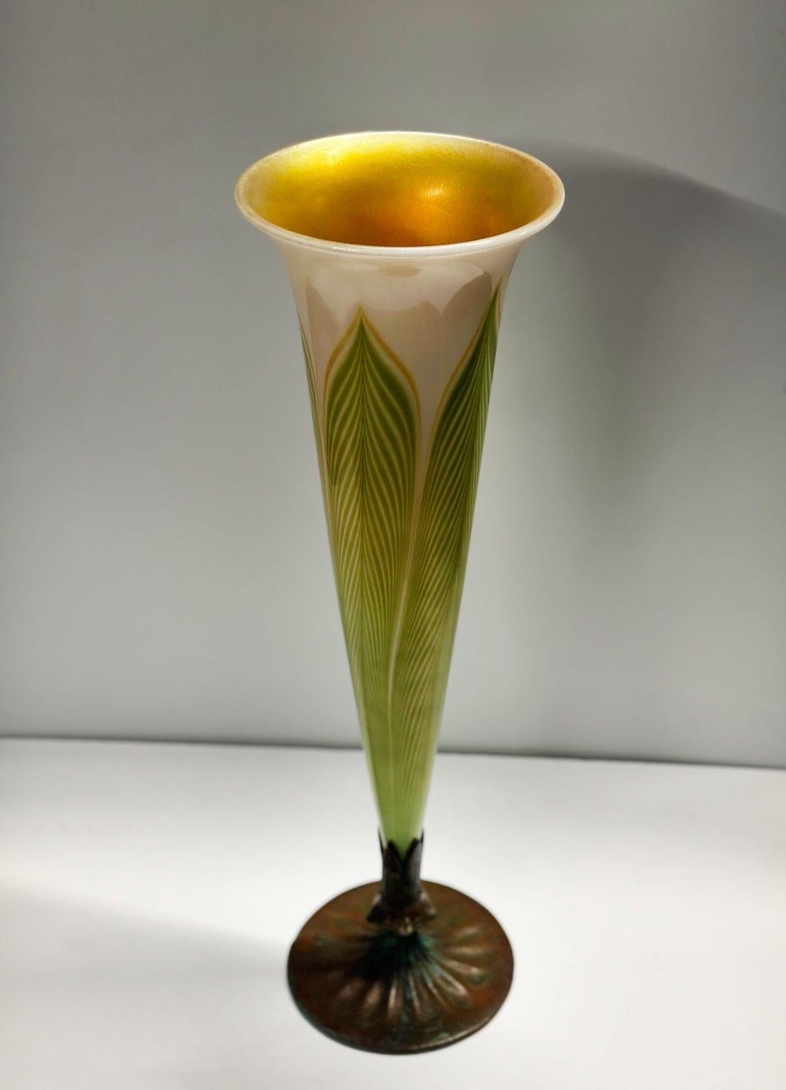 L.C. Tiffany Studios iridescent vase standing on an inserted bronze base (non-removable). The delicate yet vibrant interplay of colors, featuring shades of green, yellow, and white, blend perfectly and makes this piece stand out by its unique