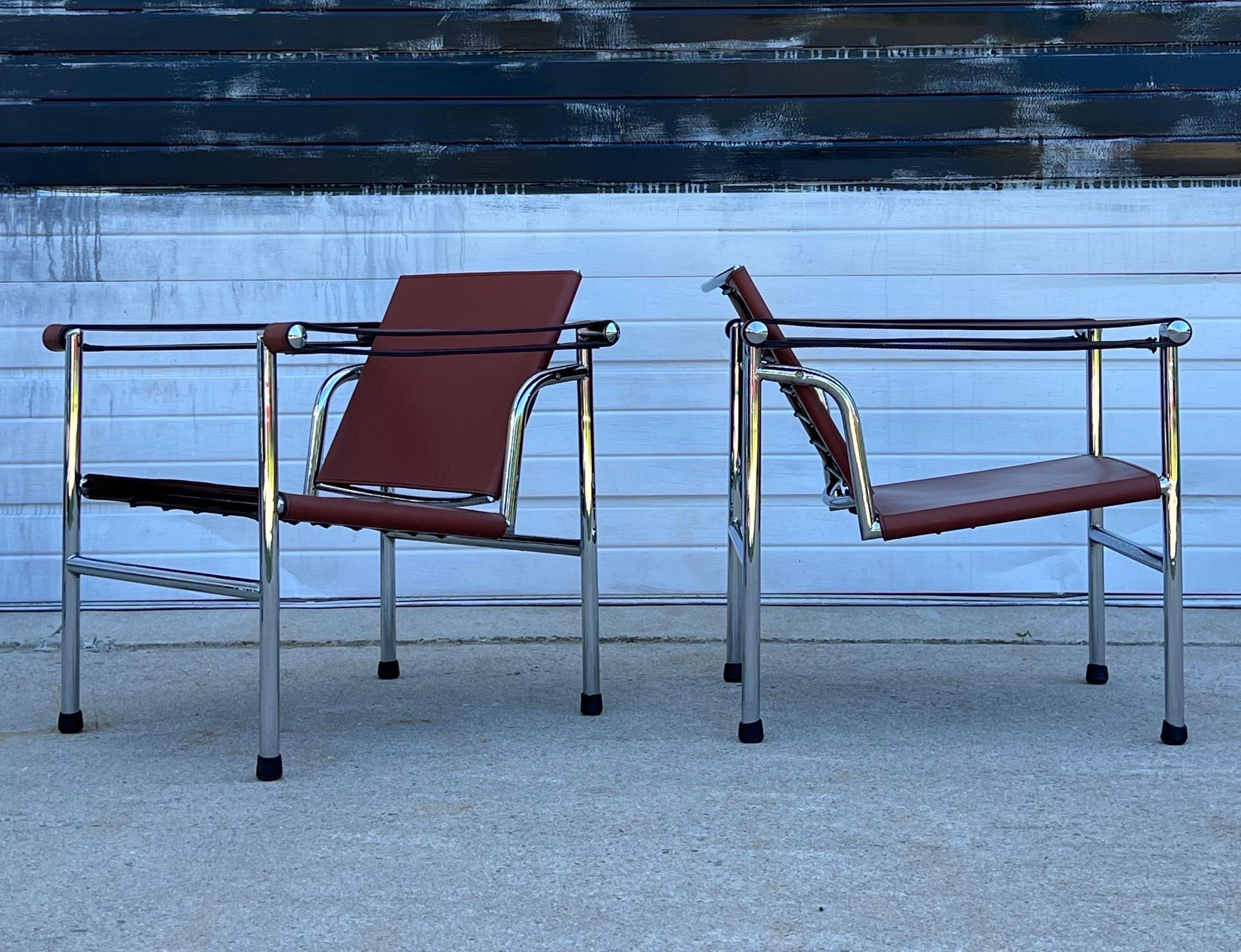 Vintage pair of Lc1 Italian armchairs designed by Le Corbusier, circa 1970s. This pair features a chrome frame with fantastic details such as the pointed end caps. Rich terracotta leather wraps the chrome frame which is comfortable, durable, and
