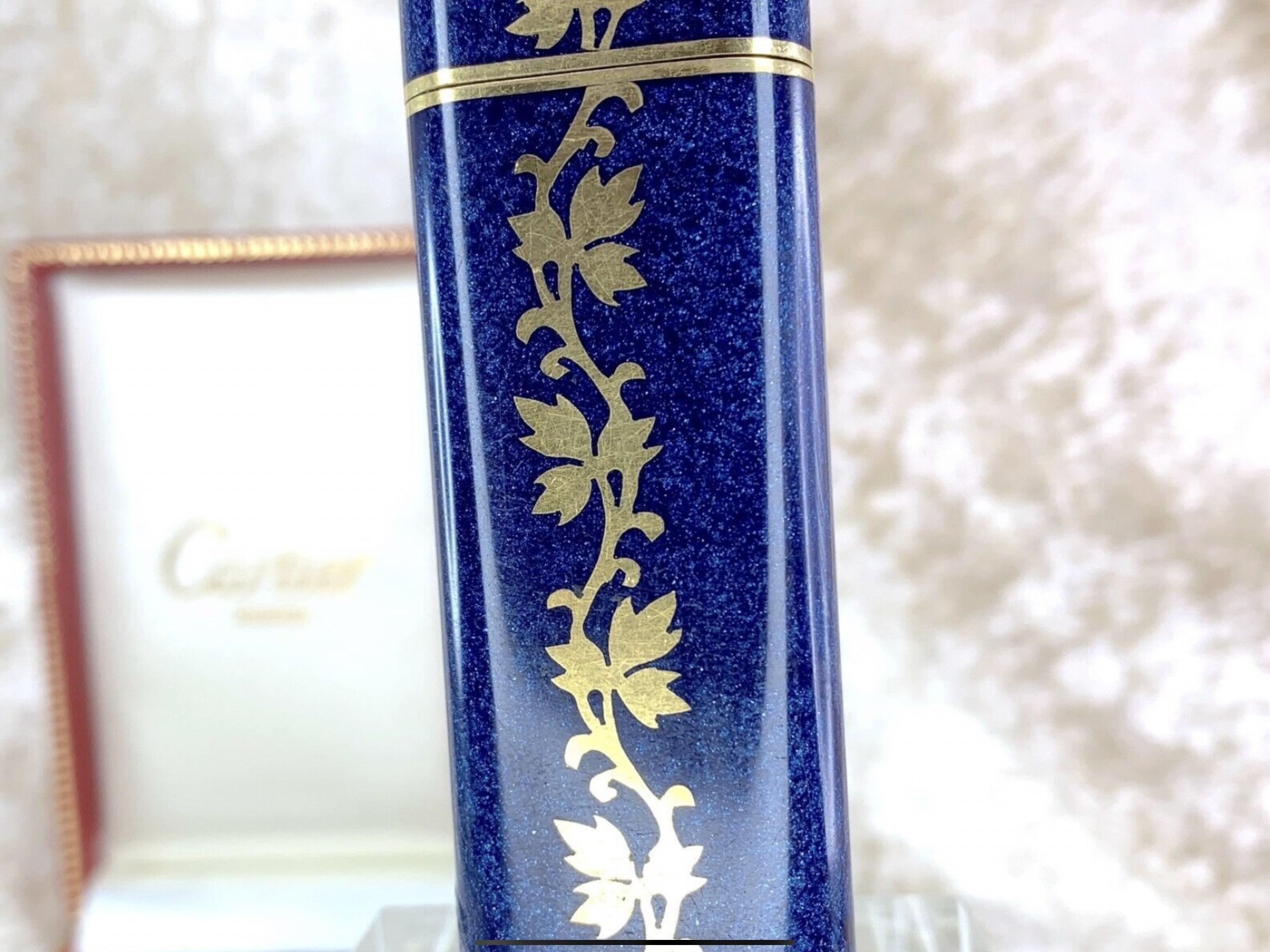 Beautiful and Very Rare Vintage Cartier Lighter in Blue Lacquer 
Gold Plated 18K
Gold flower oriental pattern 
Le Must De Cartier 
Circa 2000
In mint working condition
The lighter sparks, ignites and flames 
Comes with Original Cartier Case 
Elegant
