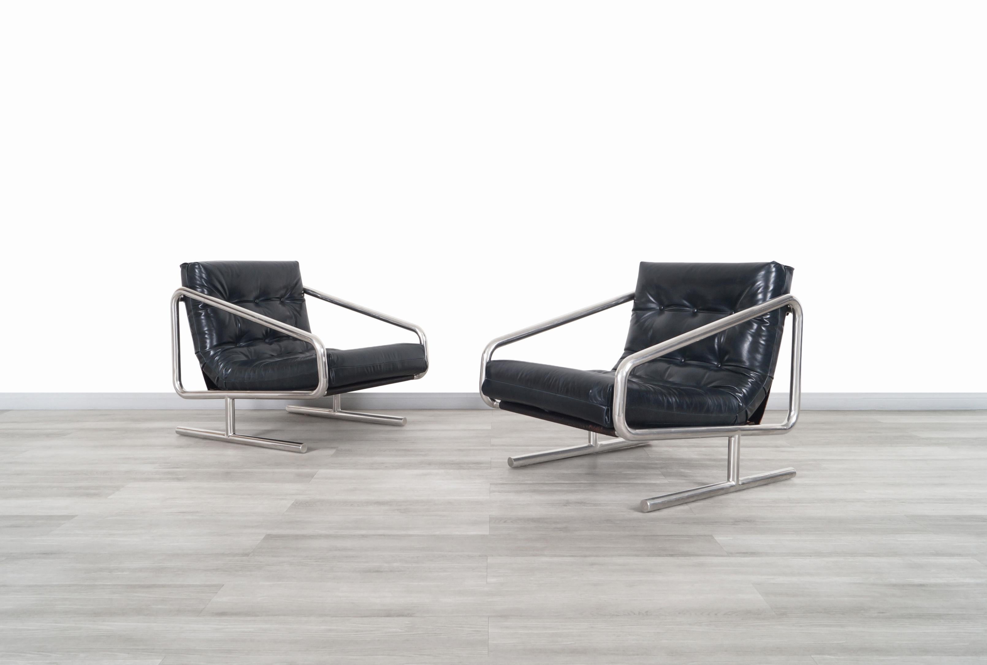 Fabuleux fauteuils de salon vintage en cuir et aluminium conçus et fabriqués aux États-Unis, vers les années 1970. Comprend de confortables coussins en cuir bleu nuit ; chaque coussin est doté d'élégants boutons disposés symétriquement. Nos artisans