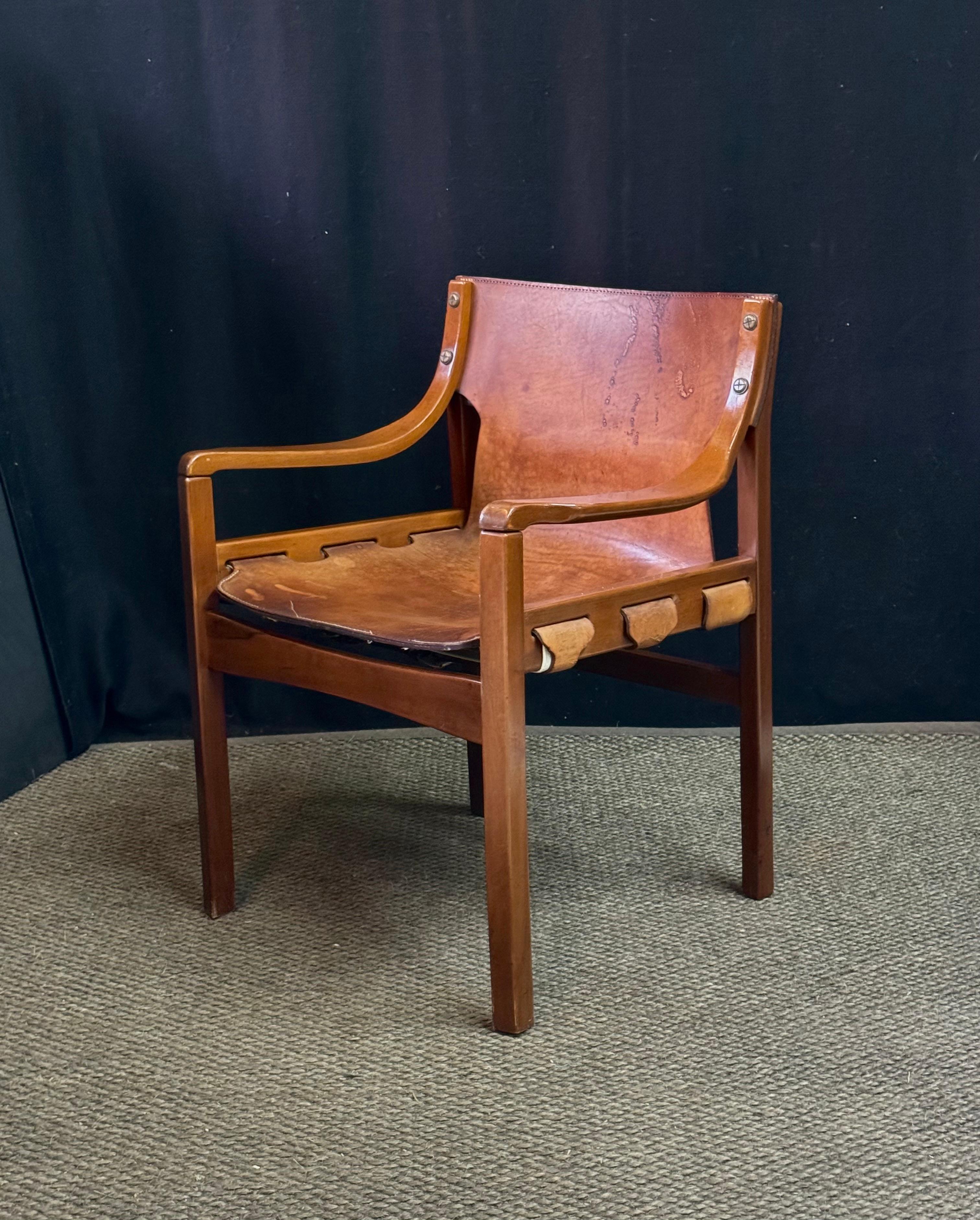 Mid Century armchair by prolific Brazilian architect and furniture designer, Sergio Rodrigues (1924-2014), having the original natural leather suspension seat held by a walnut frame with bentwood arms. Known for his stylish yet comfortable seating,