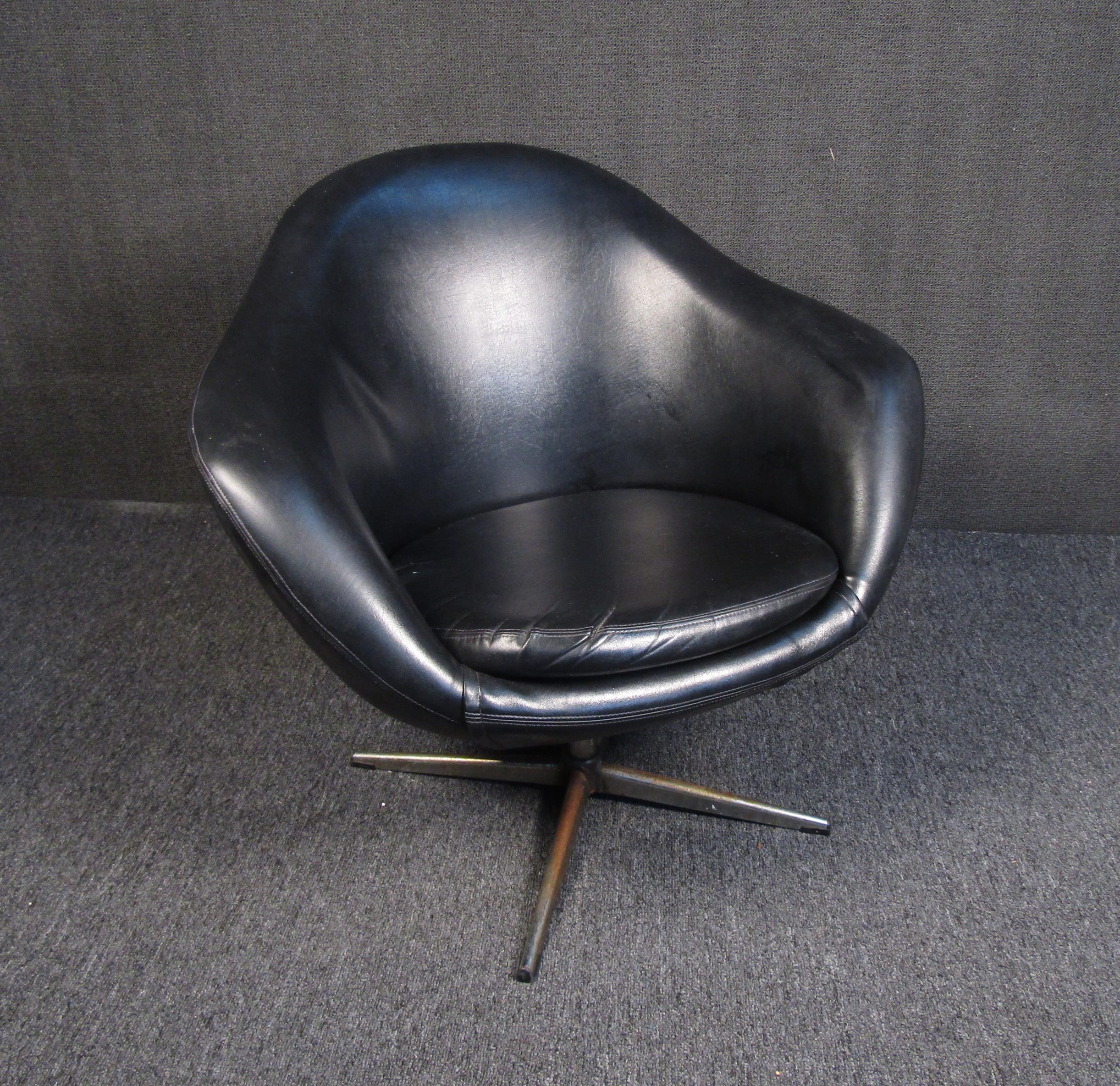 A Mid-Century Modern black lounge chair that is both comfortable and elegant. This vintage chair's rounded design allows one to sink in comfortably while being held up by a swiveling chrome base. Please confirm item's location with seller (NY or NJ)