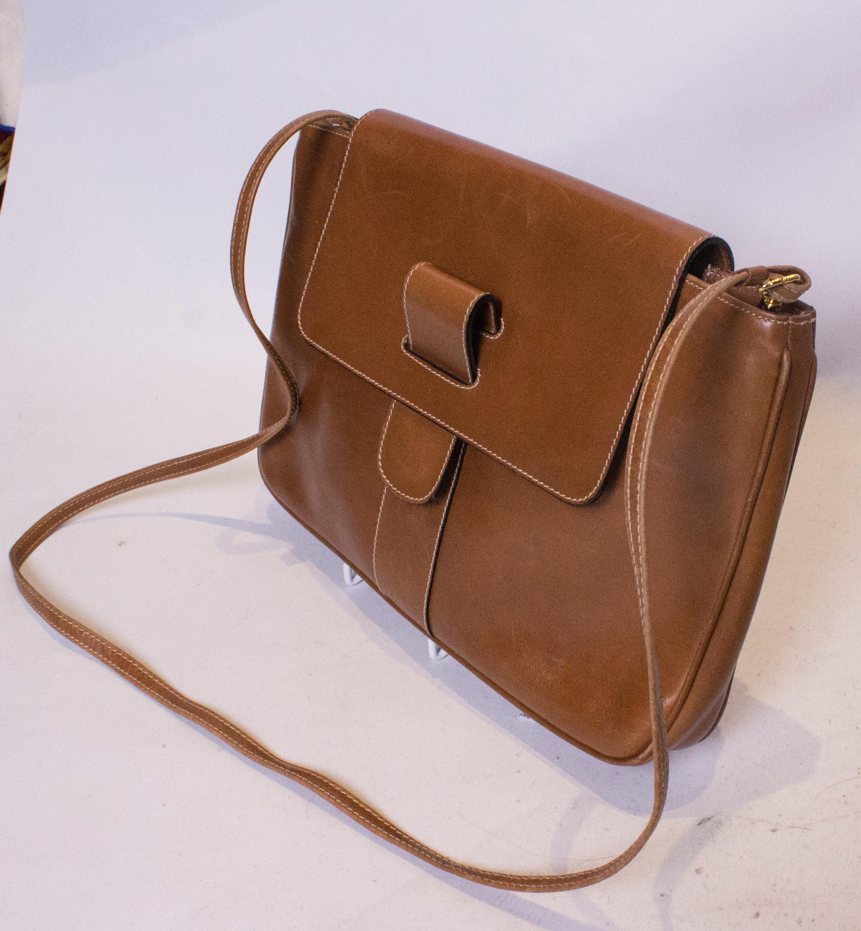 A stylish leather bag by Italian firm Ferragamo.  In a chic tan colour, the bag has a popper fastening at the front, with an internal zip pocket.  The bag has a long strap and so  can be worn cross body or as a clutch. In excellent condition and