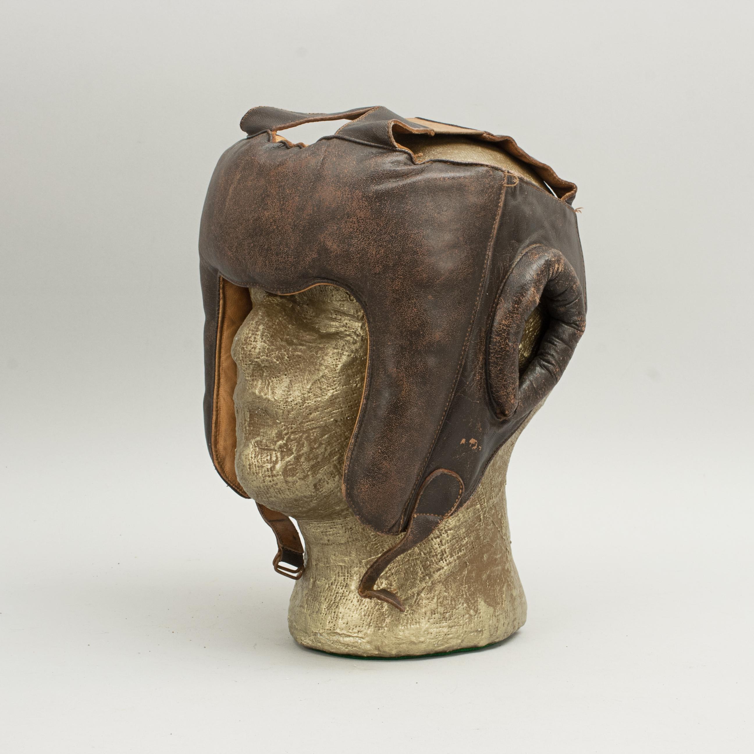 Vintage boxing helmet.
A good vintage leather boxing head protector with leather chin strap, good padding to the ears and forehead area with leather interior.

The last image shows the head guard with two pairs of boxing gloves, both sold