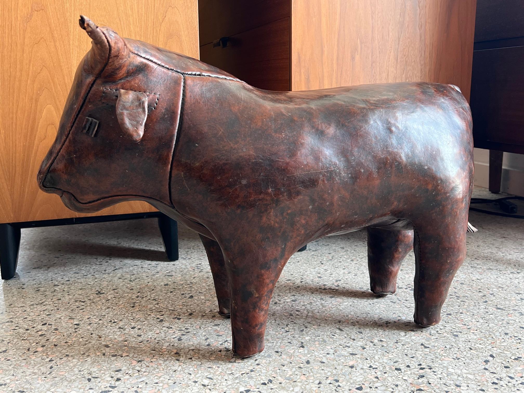A leather bull-ottoman/footstool by Abercombie & Fitch, circa 1960s. Thick brown leather with beautiful patina and character.