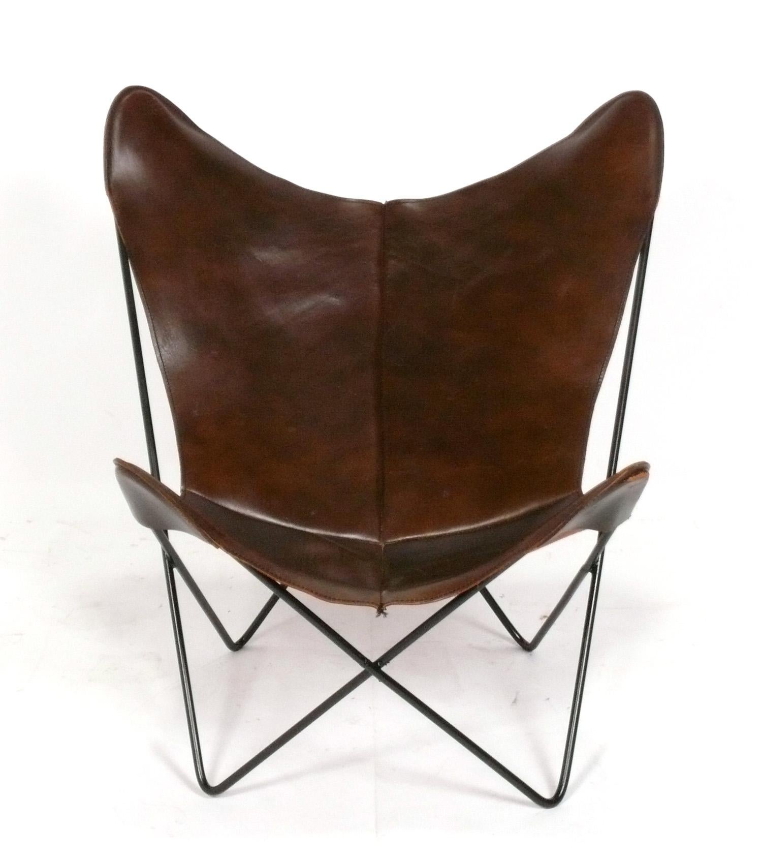 Sculptural Butterfly Chair, designed by Jorge Ferrari-Hardoy for Knoll, American, circa 1960s. This example retains it's dark chocolate brown leather sling and the black iron base has been repainted at some point.