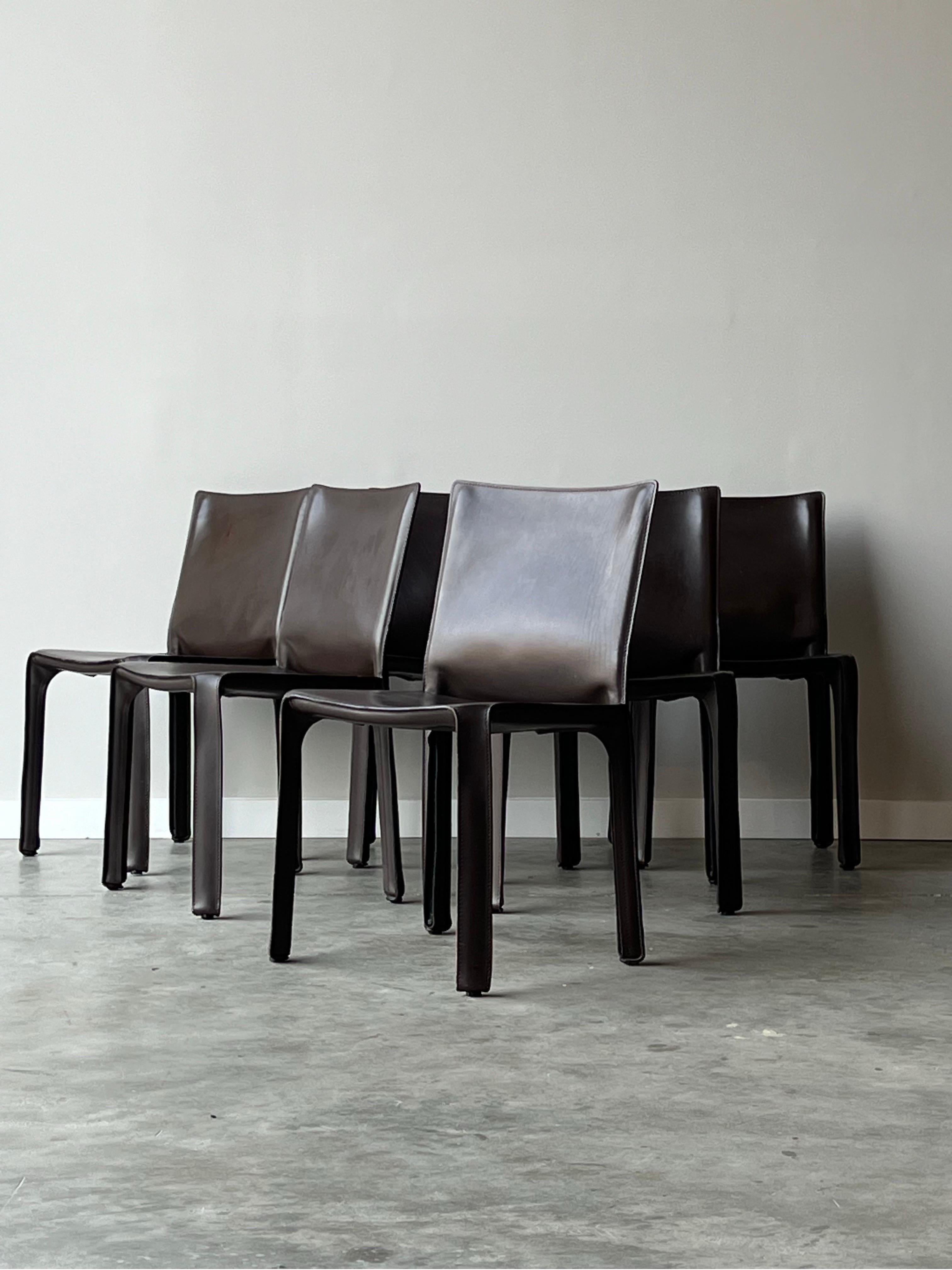 Set of six dining chairs designed by Mario Bellini for Cassina, Italy - circa 1980s. These chairs, otherwise known as the ‘CAB’ chairs, are completely wrapped in a rich dark brown leather. Zippers can be found on the bottom of the chair and follow