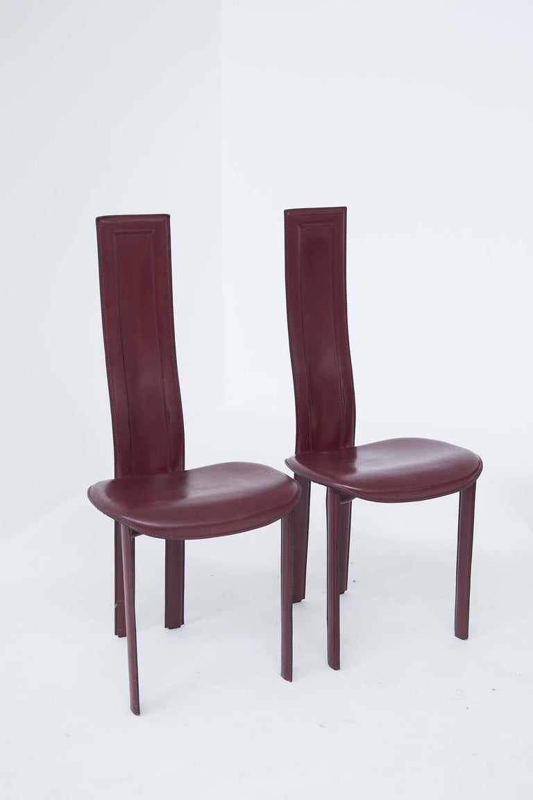 Set of 6 table chairs in burgundy leather with visible stitching, four are for the side of the table, two are the head chairs, with a higher and longer back, their seat is rounded.
All the vintage leather chairs have the original label under the