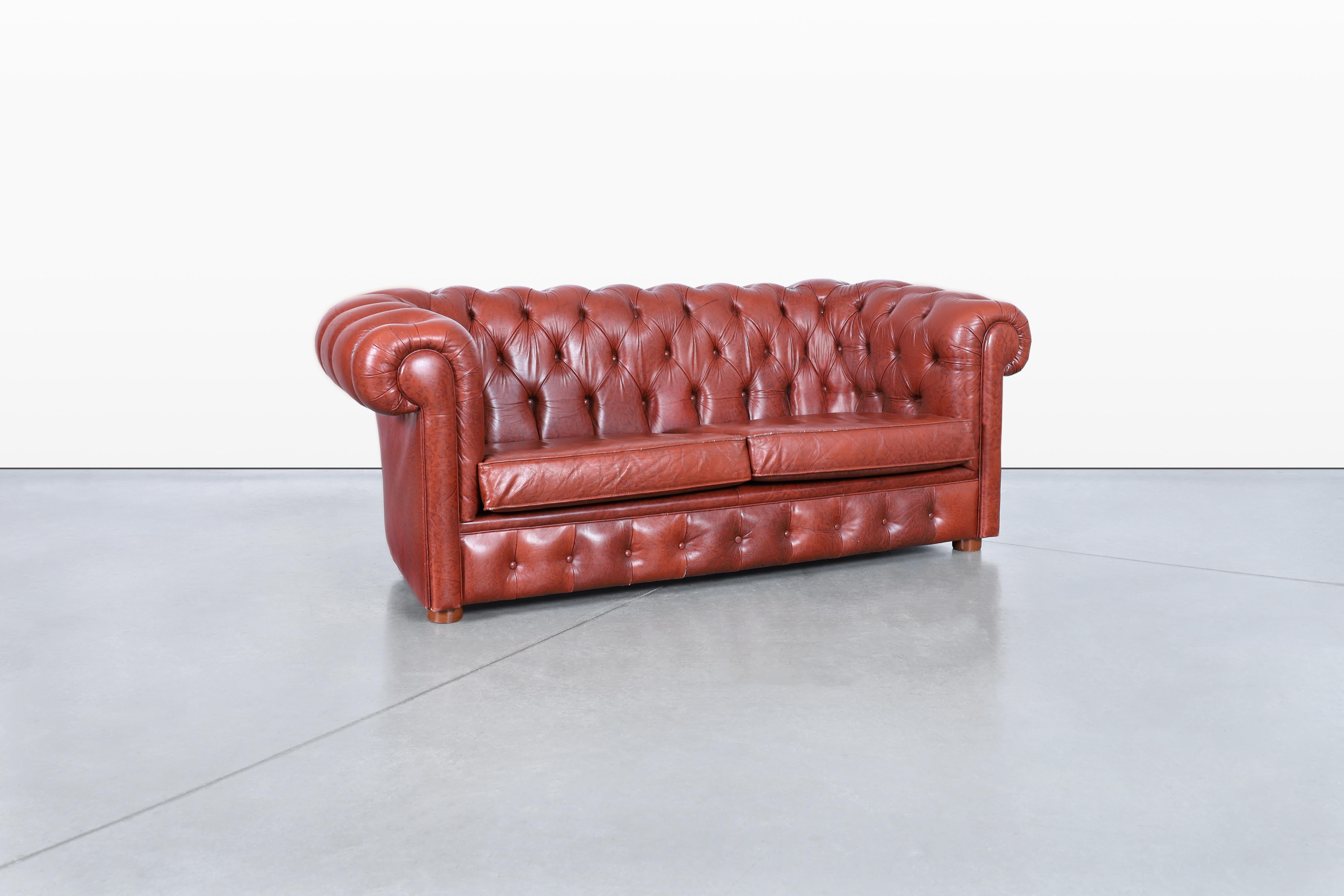Precioso loveseat chesterfield vintage de cuero, una verdadera representación de la artesanía excepcional de Estados Unidos, hacia la década de 1980. Esta pieza atemporal presenta un elegante diseño caracterizado por una tapicería de rombos