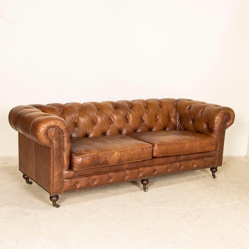 Vintage leather furniture is highly sought after these days, making this 7' sofa a great find. The tufted Chesterfield back with heavy rolled arms is classic and inviting. The brown leather is in good condition, all buttons are in place, and it sits