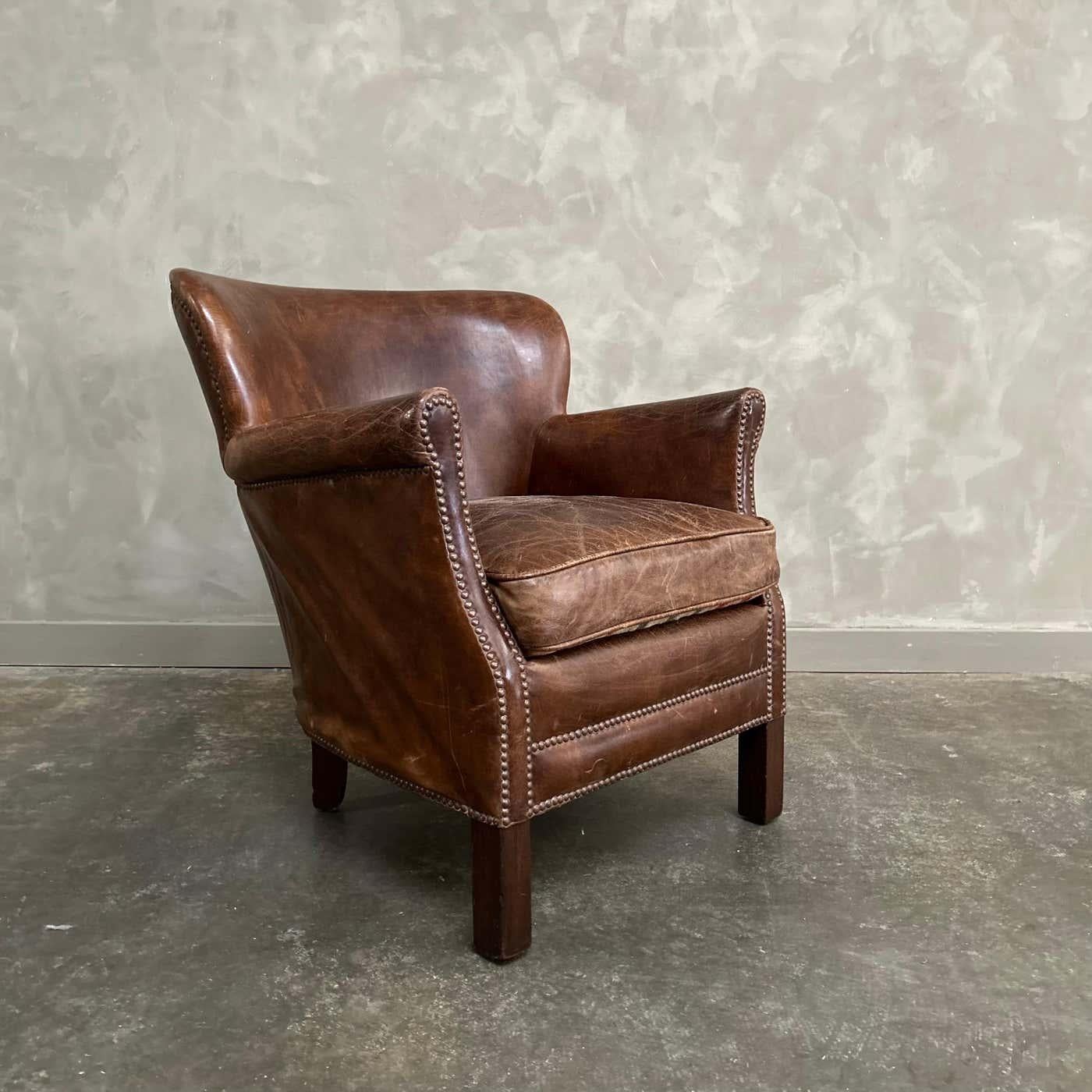 Le fauteuil club en cuir anglais est petit par la taille, grand par le style, ce fauteuil vintage offre toute la présence et le confort d'un fauteuil plus grand. Un fauteuil à oreilles anglais des années 1920, dont les proportions réduites et