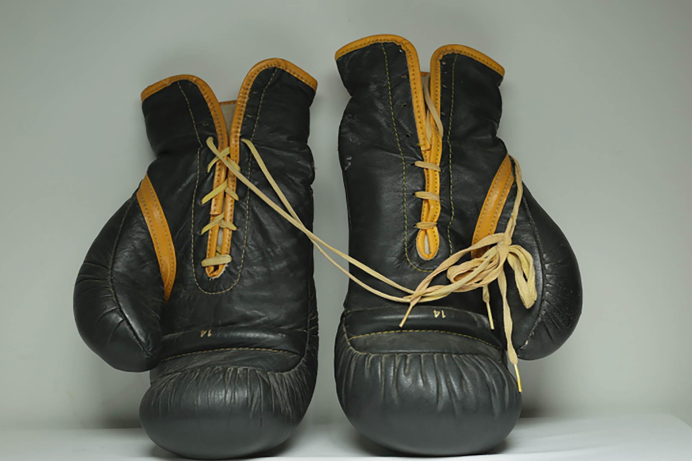 About:

This is a original pair of Everlast leather boxing gloves. The boxing gloves are black leather with gold leather piping, yellow laces and a leather 