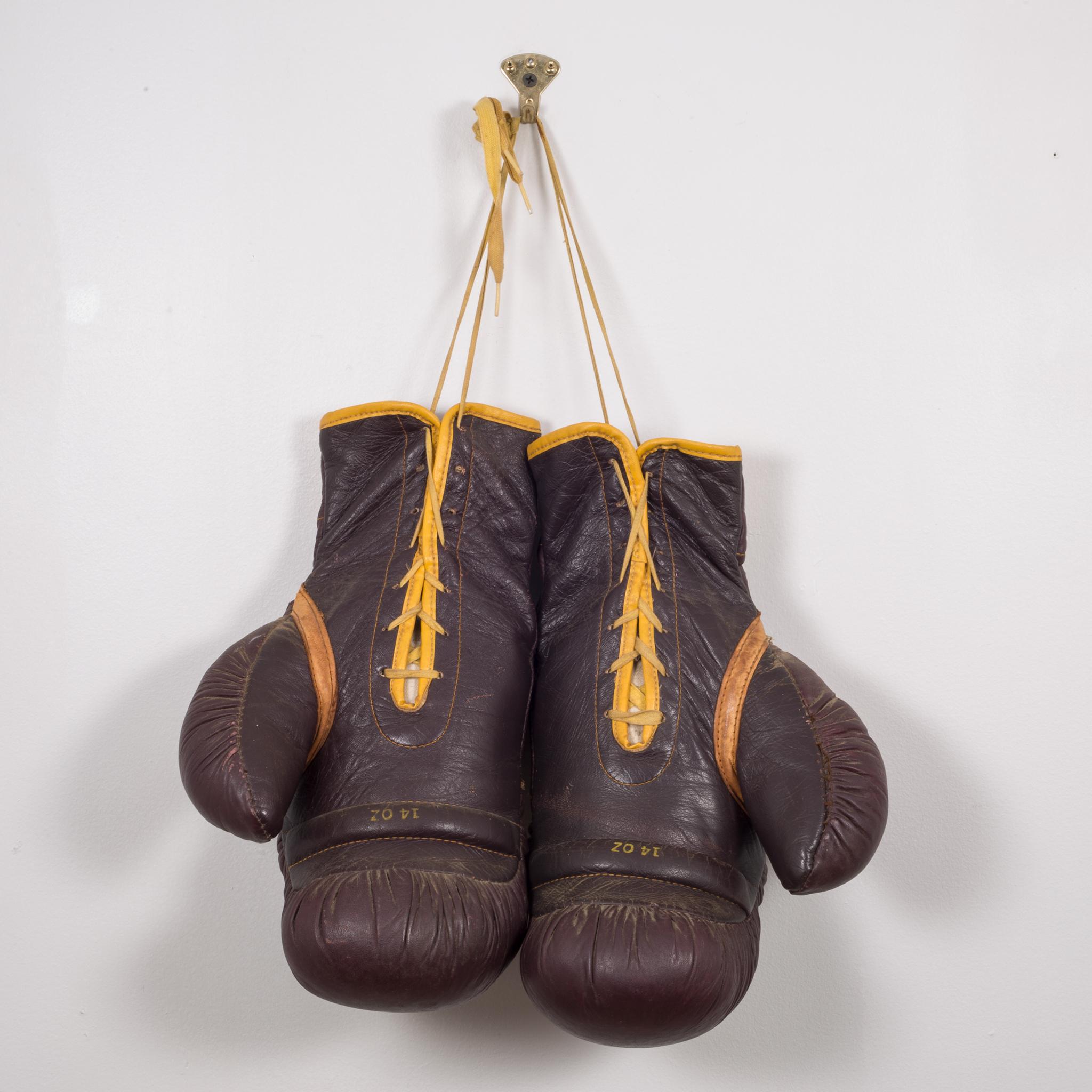 About:

This is a original pair of Everlast leather boxing gloves. The boxing gloves are brown leather with gold leather piping, yellow laces and a leather 