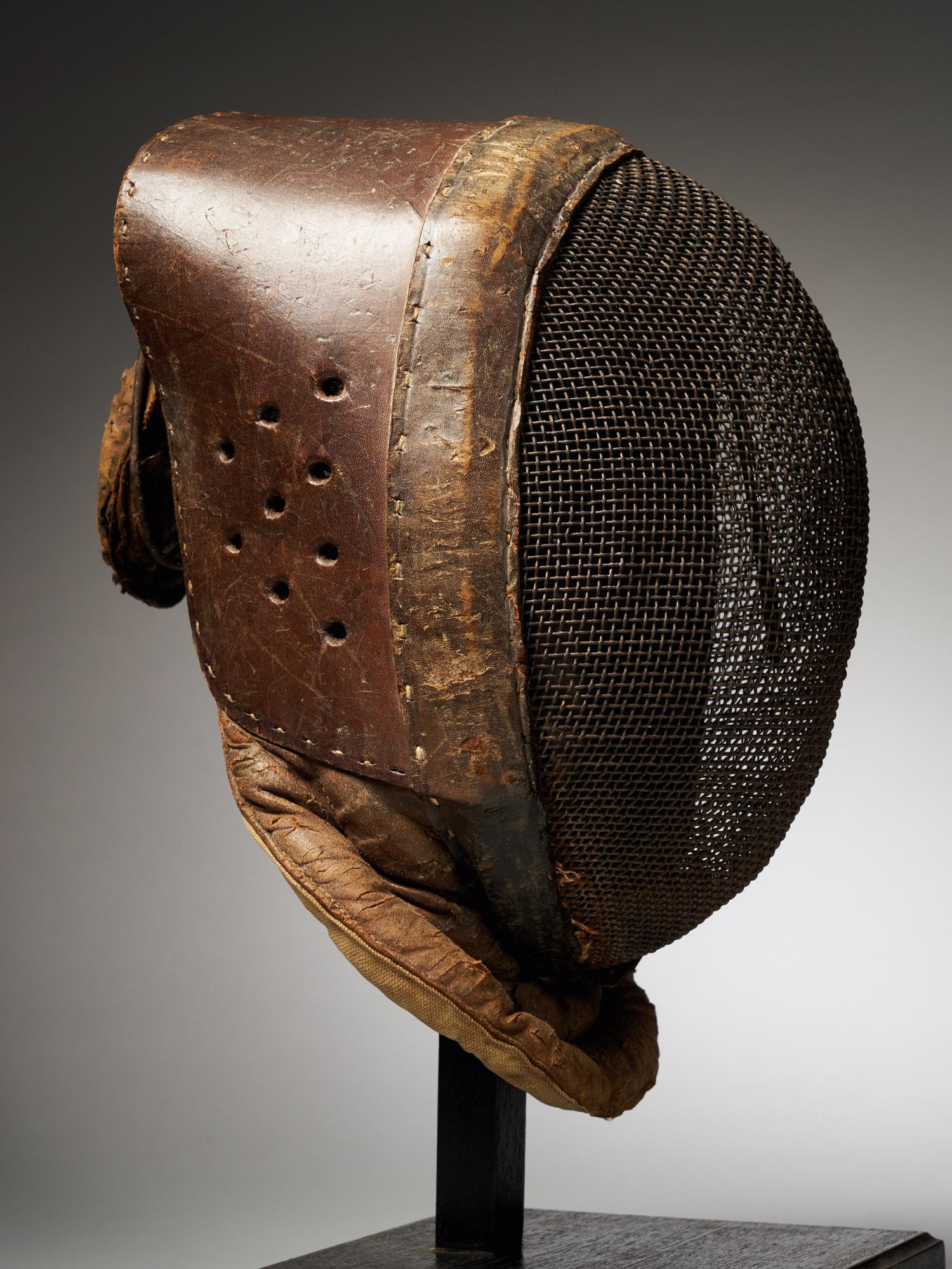 This is a leather fencing mask from the 20th century and it is manufactured in France. The mask has clearly been worn, as can be told from the leather.