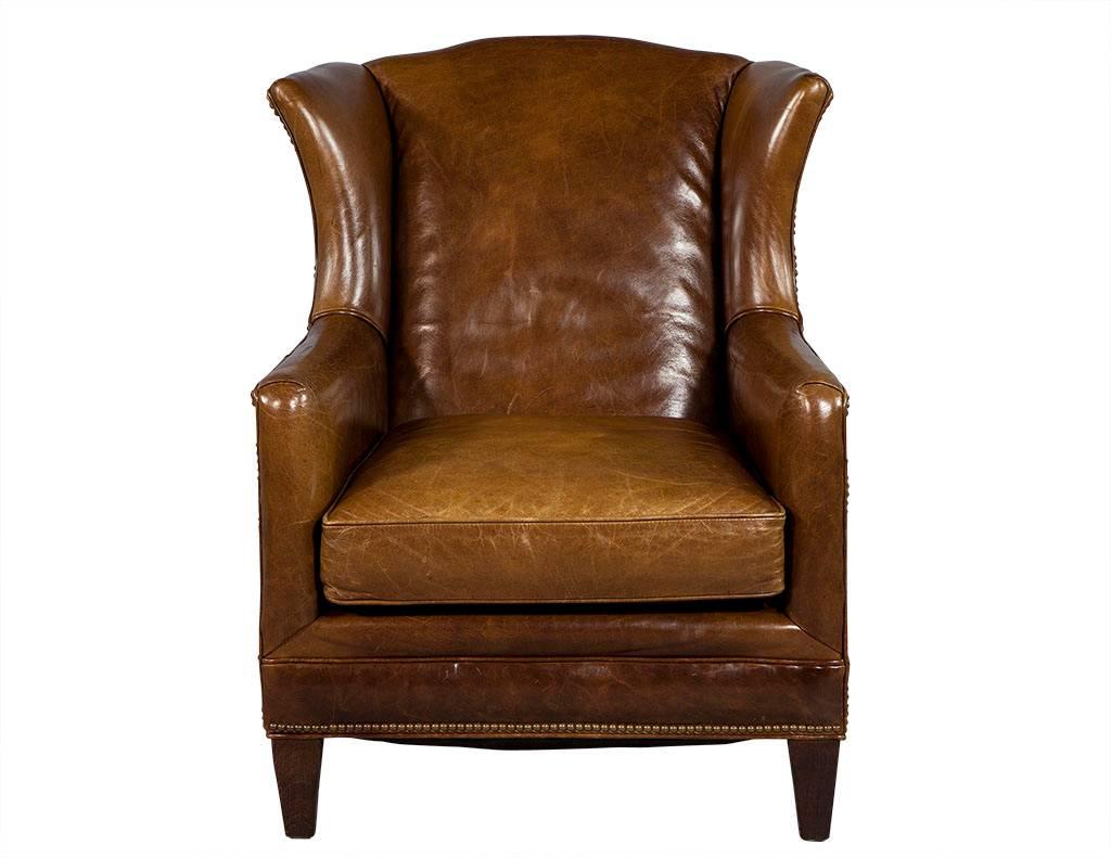This traditional wing chair hails from France. It is coated in a gorgeous brown distressed leather with a wonderful patina and brass studs on the edges. The piece sits atop tapered wood feet and is a perfect fit for a rustic home.