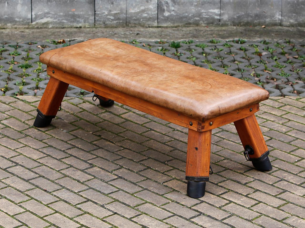 This gymnastics bench comes from a gym in Prague and was designed in the 1930s. The iron feet have been preserved with original cow leather lining. The thick cowhide has been cleaned and preserved and has a very nice patina.