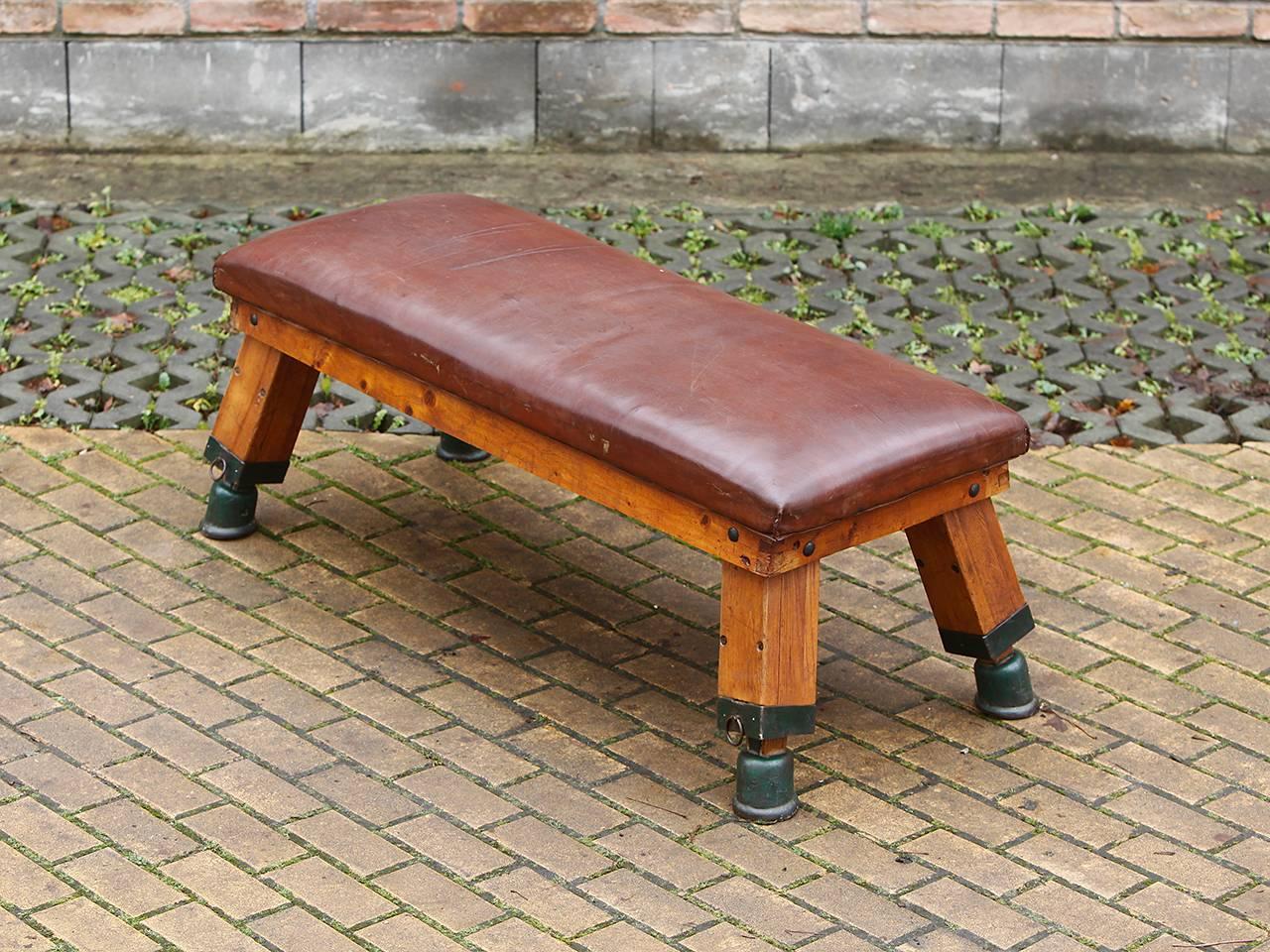 This gymnastics bench comes from a gym in Prague and was designed in the 1930s. The iron feet have been preserved with original cow leather lining. The thick cowhide has been cleaned and preserved and has a very nice patina.