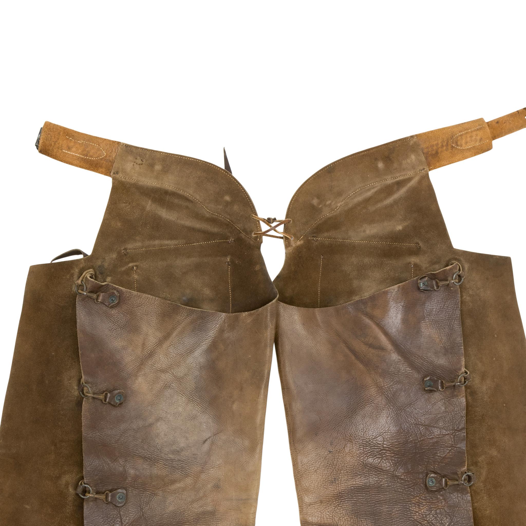  Vintage leather Heiser batwing chaps. With two outside pockets, basketweave stamped belt and metal conchos. Great condition with excellent patina and nice coloring. Would display nicely in a Western style home. Late 20th century. Size: 36