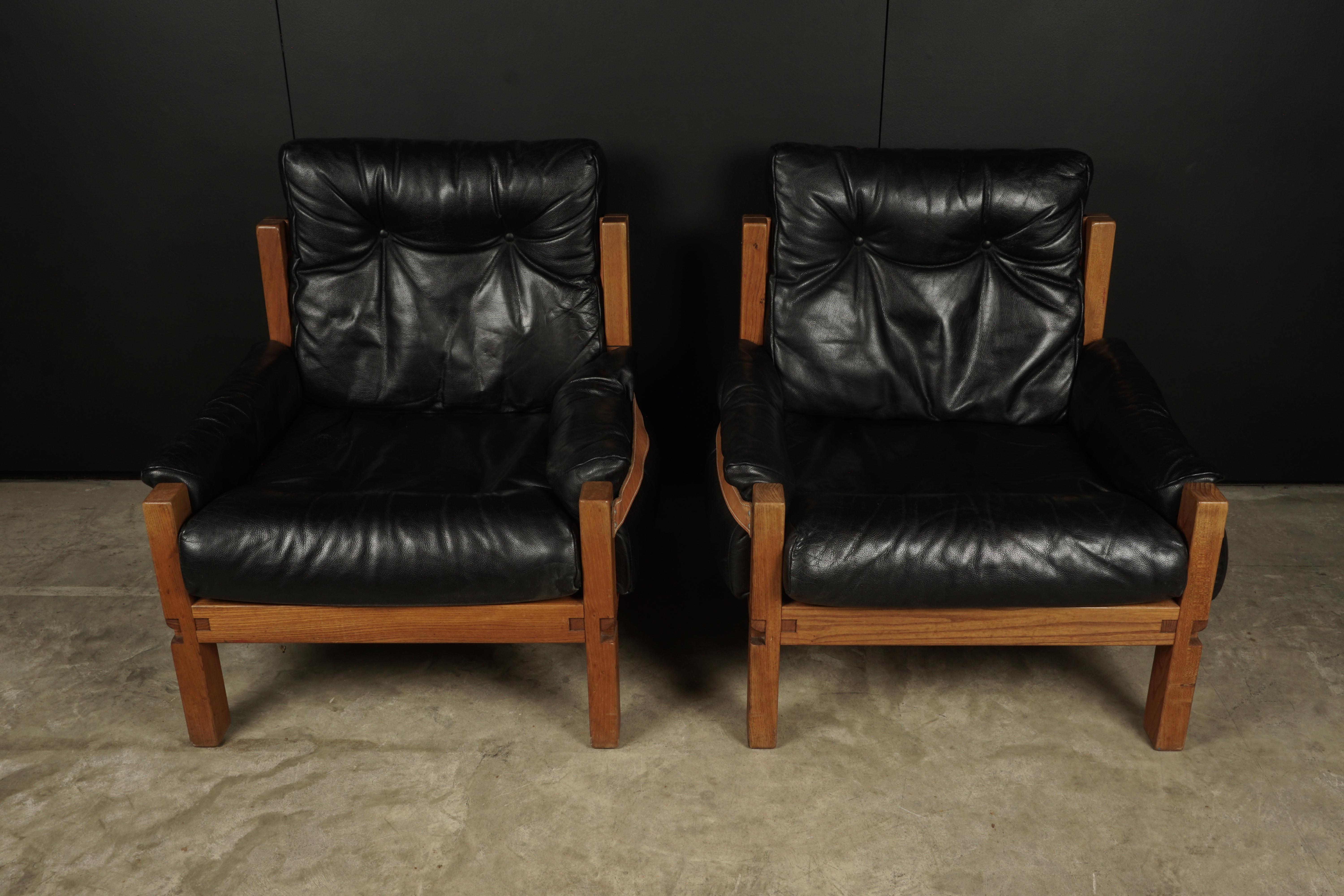 Vintage leather lounge chairs designed by Pierre Chapo, France, 1950s. Solid elm construction with cognac leather straps. Black leather cushions with light patina and wear. Superb quality.
  