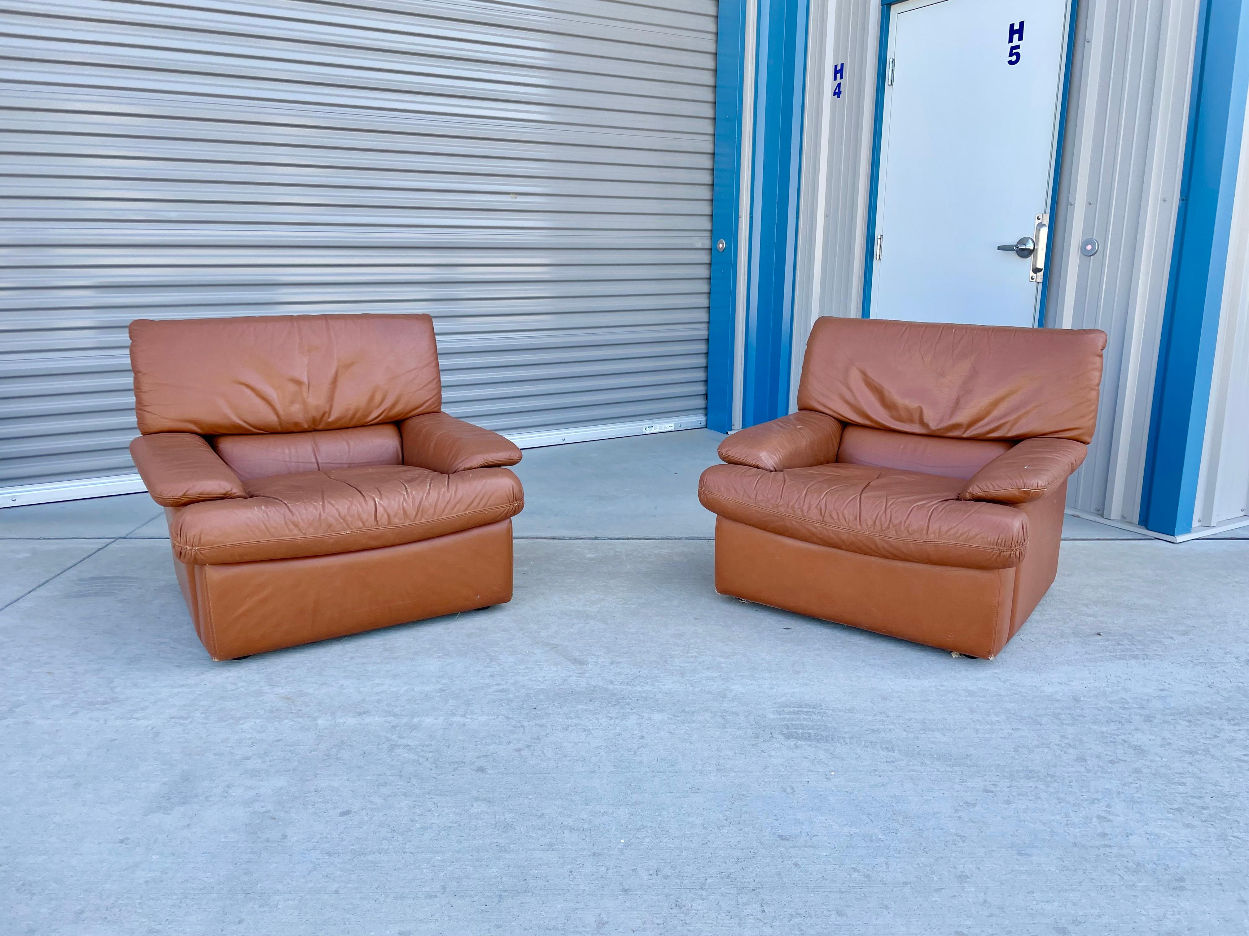Vintage leather lounge chairs styled after De Sede and manufactured in Italy circa, 1970s. These lounge chairs, given to there size, are a perfect pair for your living room space. The chairs also has an orange leather upholstery giving them that