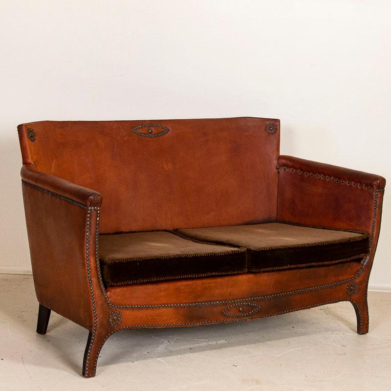 This handsome loveseat and pair of small scale barrel back club chairs are a great find for one searching for an authentic vintage leather set. The rich brown leather is accented with piping and cabriolet legs. While there are minor/expected scuffs