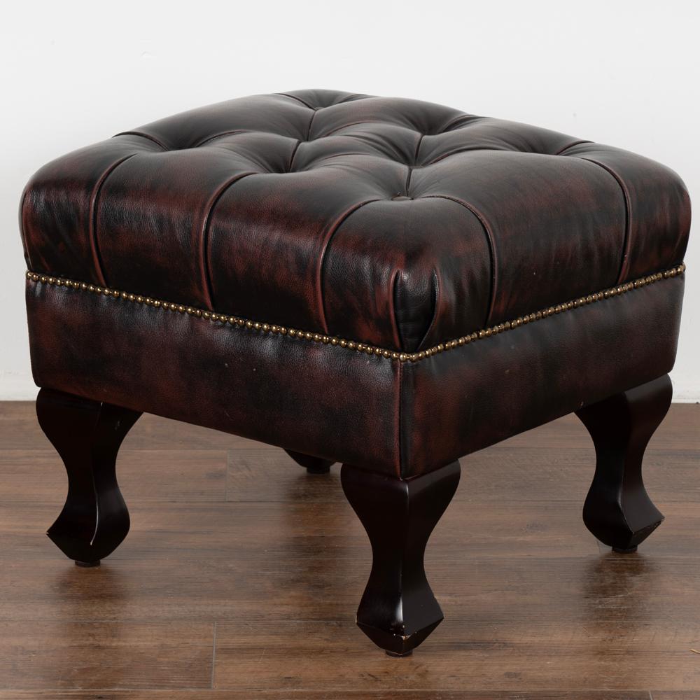 Small vintage leather ottoman/footstool with tufted seat and nailhead trim.
Dark brown leather has strong plum colored undertones and is in good condition, accented by brass nail heads.
Sold in vintage used condition, solid/stable and ready for