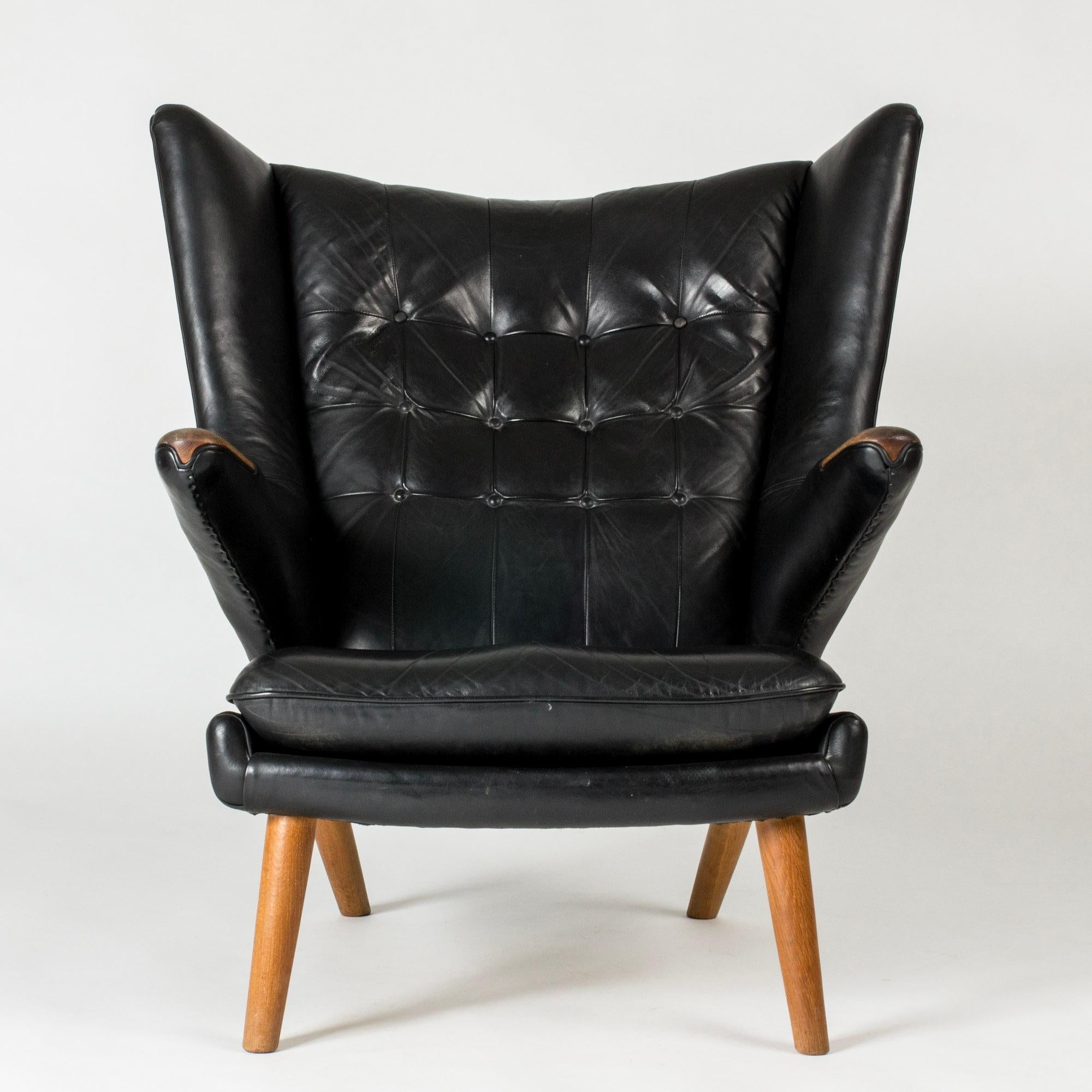 Iconic “Papa Bear” lounge chair by Hans J. Wegner, in a wide, comfortable design upholstered in black leather. Handles with oak details at the ends.