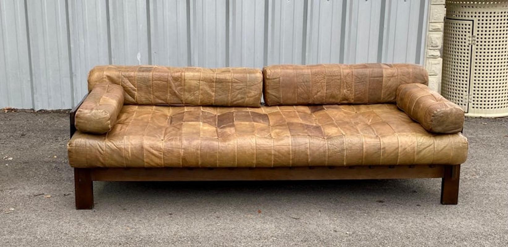 Vintage leather patchwork daybed sofa features quality leather in varying hues of warm browns with removable seat, arm, and back cushions. This daybed sofa has a deep seat, nice patina, and high-quality stitching and sits on a stained beech wooden