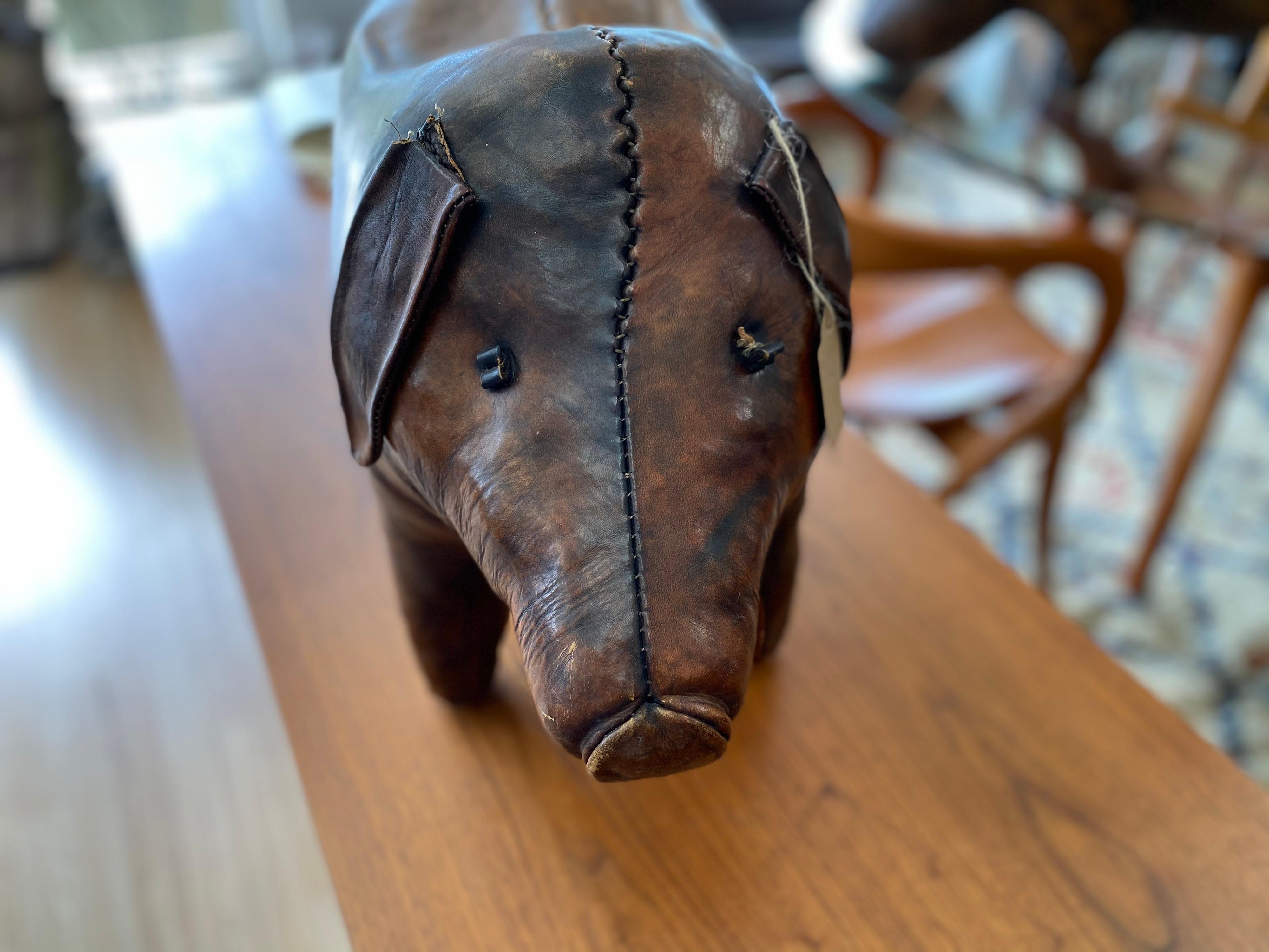 Vintage leather pig decorative footstool designed by Dimitri Omersa for Abercrombie and Fitch, circa 1960s is hand-stitched and features aged leather. The tail and eyes are intact. The back is bent due to use, but footstool is overall structurally