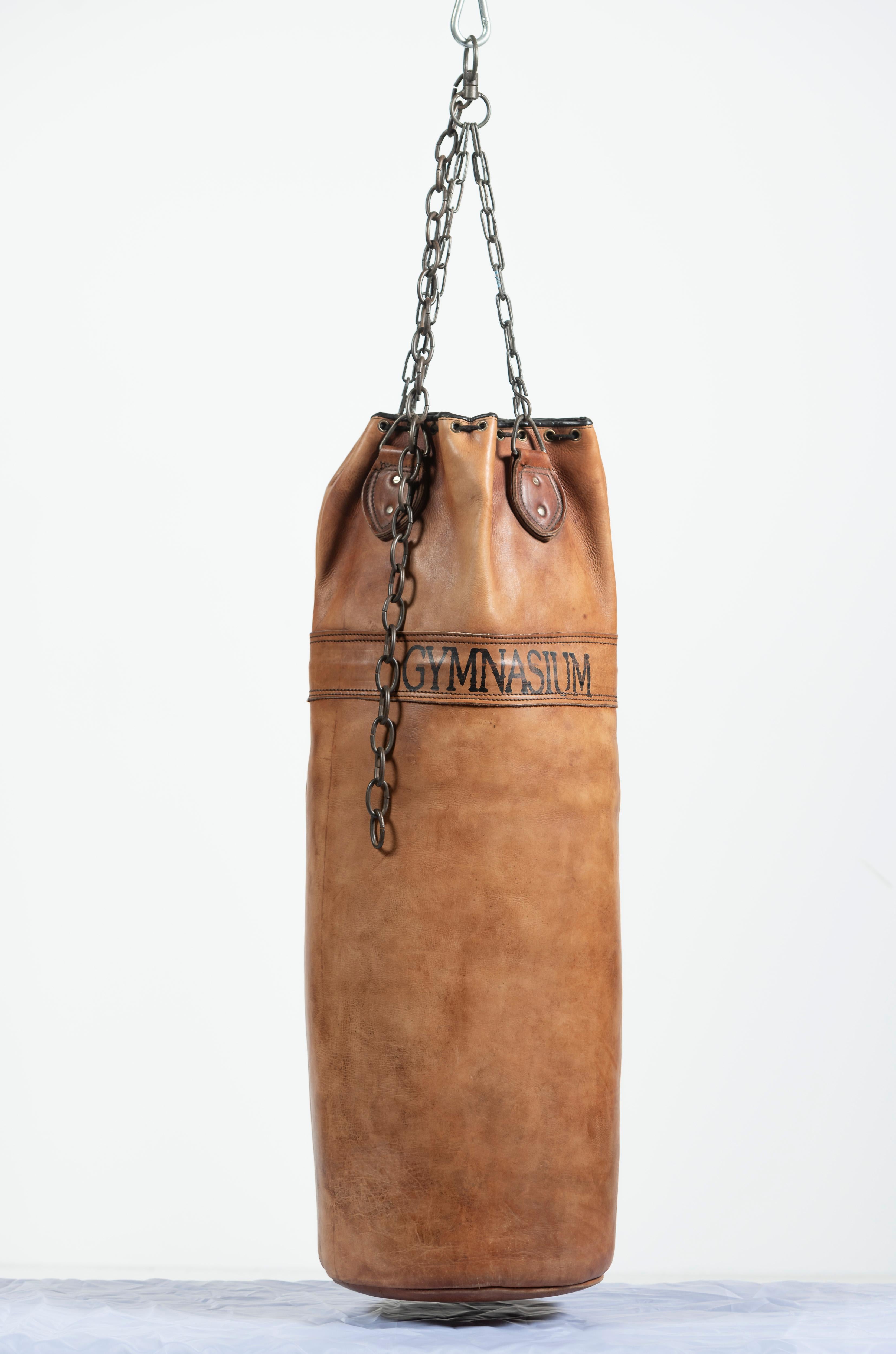 Time to upgrade your personal gym to include a stylish punching bag? This piece is made of vintage leather and has seen some action though is in great shape for all its wear and tear! Emblazoned with GYMNASIUM, the bag will make an immediate impact