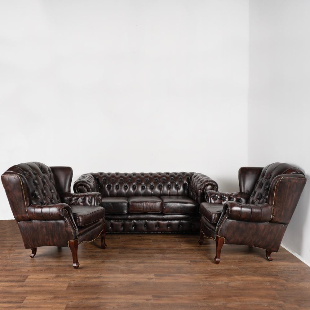 Set (3) vintage leather Chesterfield style sofa and pair of wingback arm chairs.
The dark brown leather with plum colored undertones is in good condition and accented by brass nail heads.
Sold in used vintage condition, this set sits
