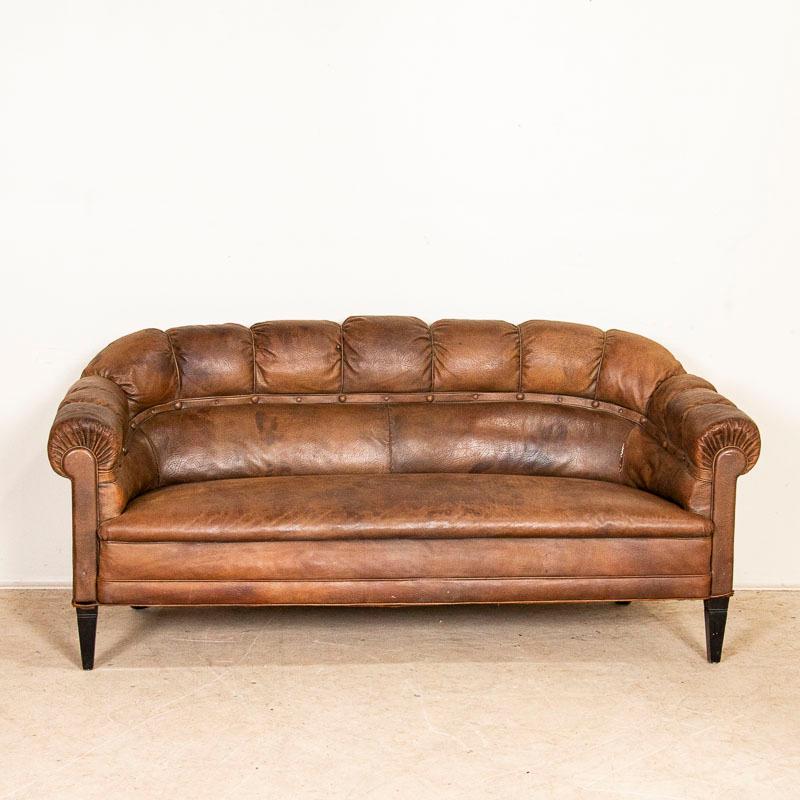 To find an original vintage leather sofa is a great find on its own, but to get the complete set with pair of club chairs included makes this a great find that does not come along often. The worn vintage leather has a trimmed rolled back and arms.