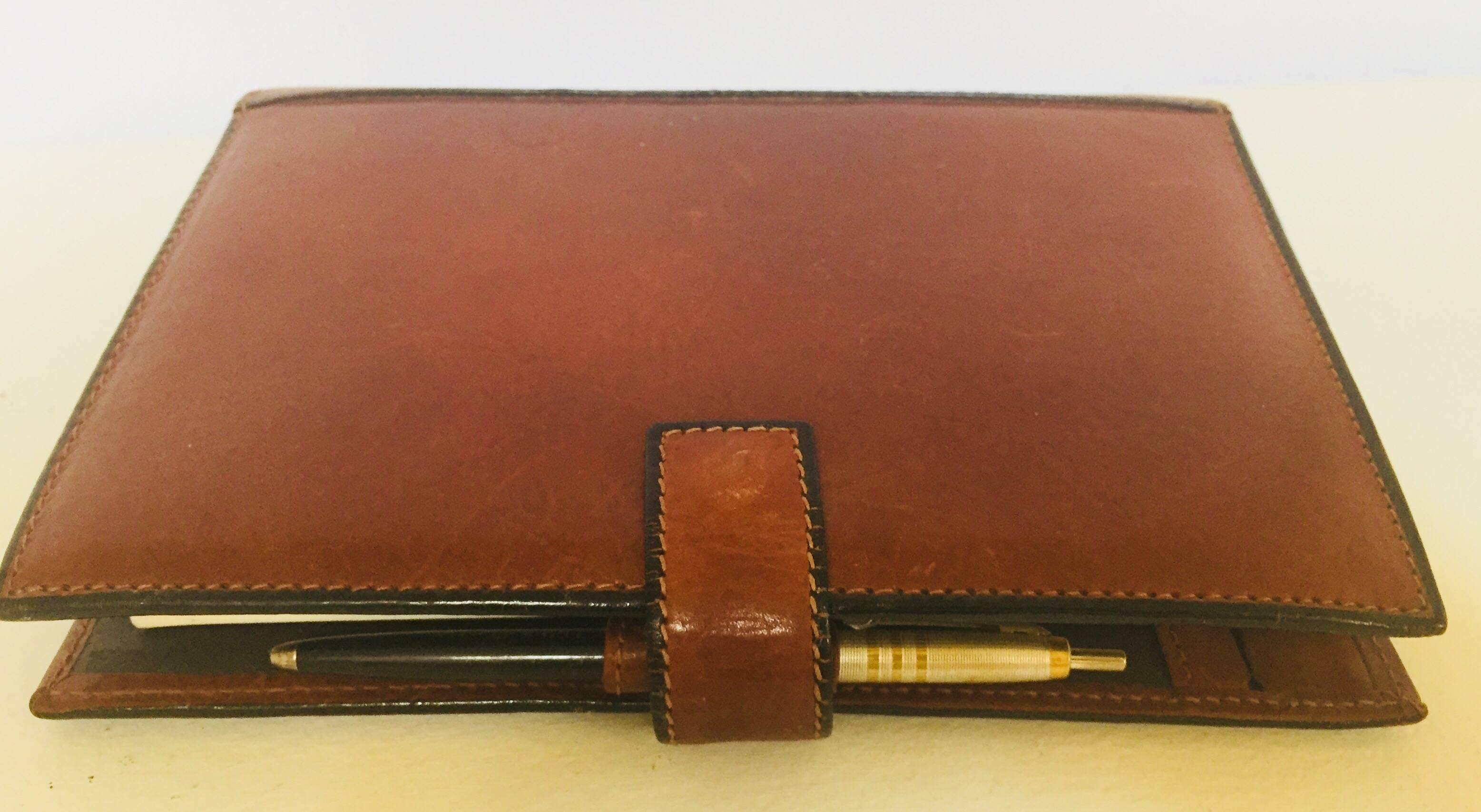 Vintage brown soft leather agenda refillable by Tumi.
The agenda is lined in brown polished stitched leather and has convenient diagonal pockets on the front and back inside covers.
Agenda pages show a monthly planner, a week-at-a-glance, yearly