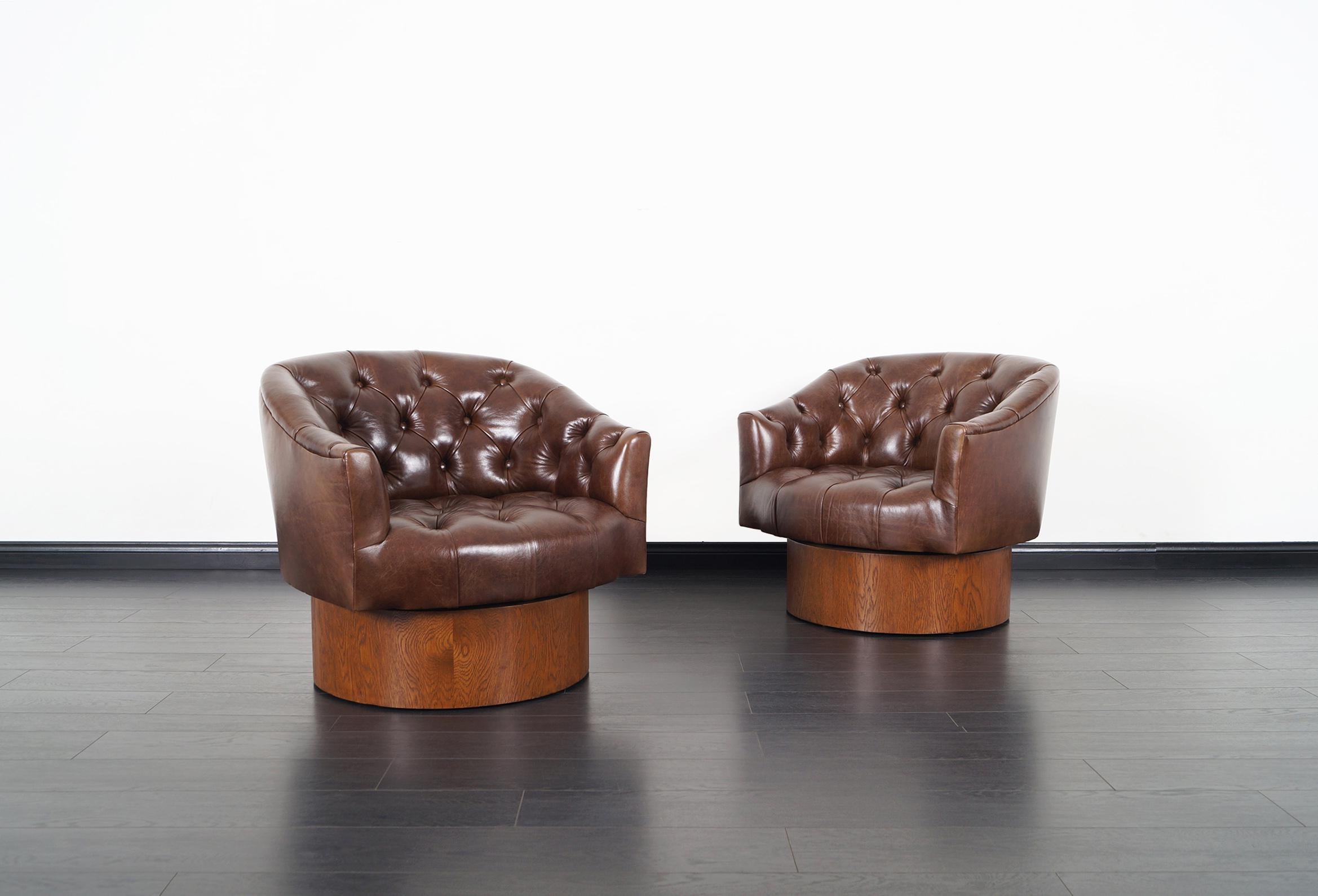 Exceptional pair of vintage swivel lounge chairs designed by Milo Baughman for Thayer Coggin in the United States, circa 1960s. These comfortable chairs have been professionally upholstered in high-quality leather. It features a walnut stain oak