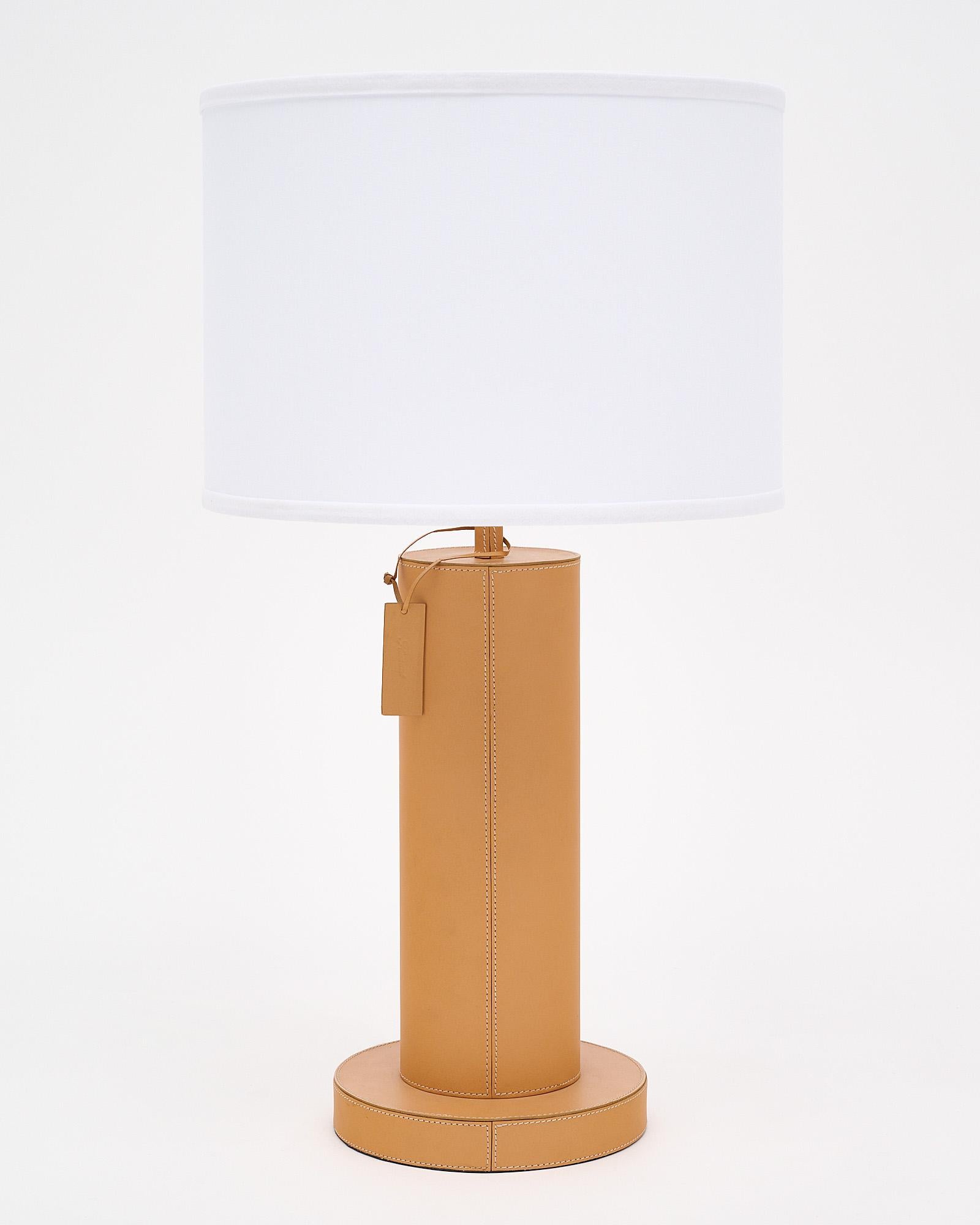 Pair of table lamps wrapped in tan leather and featuring contrasting stitching. They are tagged with a leather stamp saying Flamant. They have been newly wired to fit US standards.