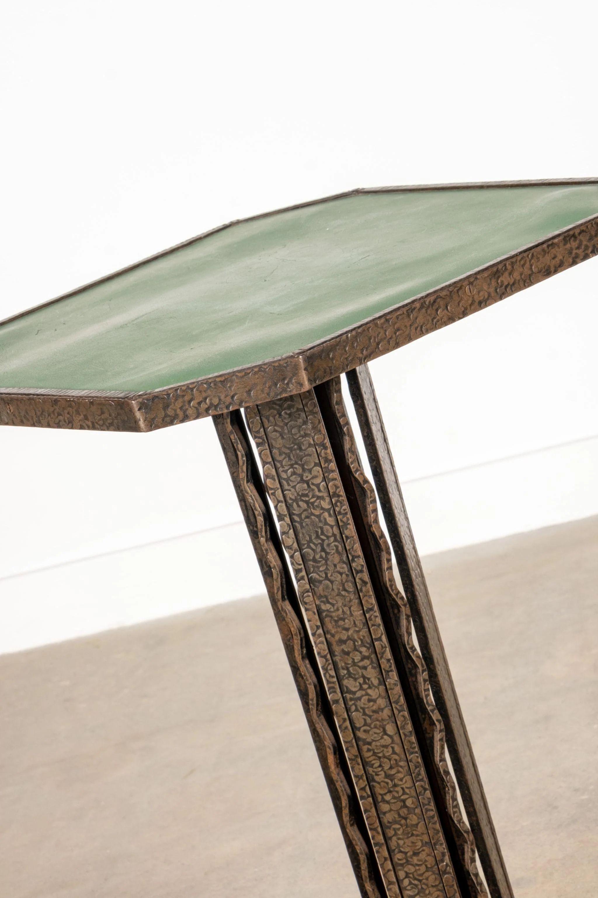 Con su base esculpida y sus líneas suavemente ornamentadas, esta mesa auxiliar con tapa de cuero verde hace un guiño a la sensibilidad romántica e inspirada en la naturaleza del Art Nouveau. La forma hexagonal le da un toque moderno, mientras que el