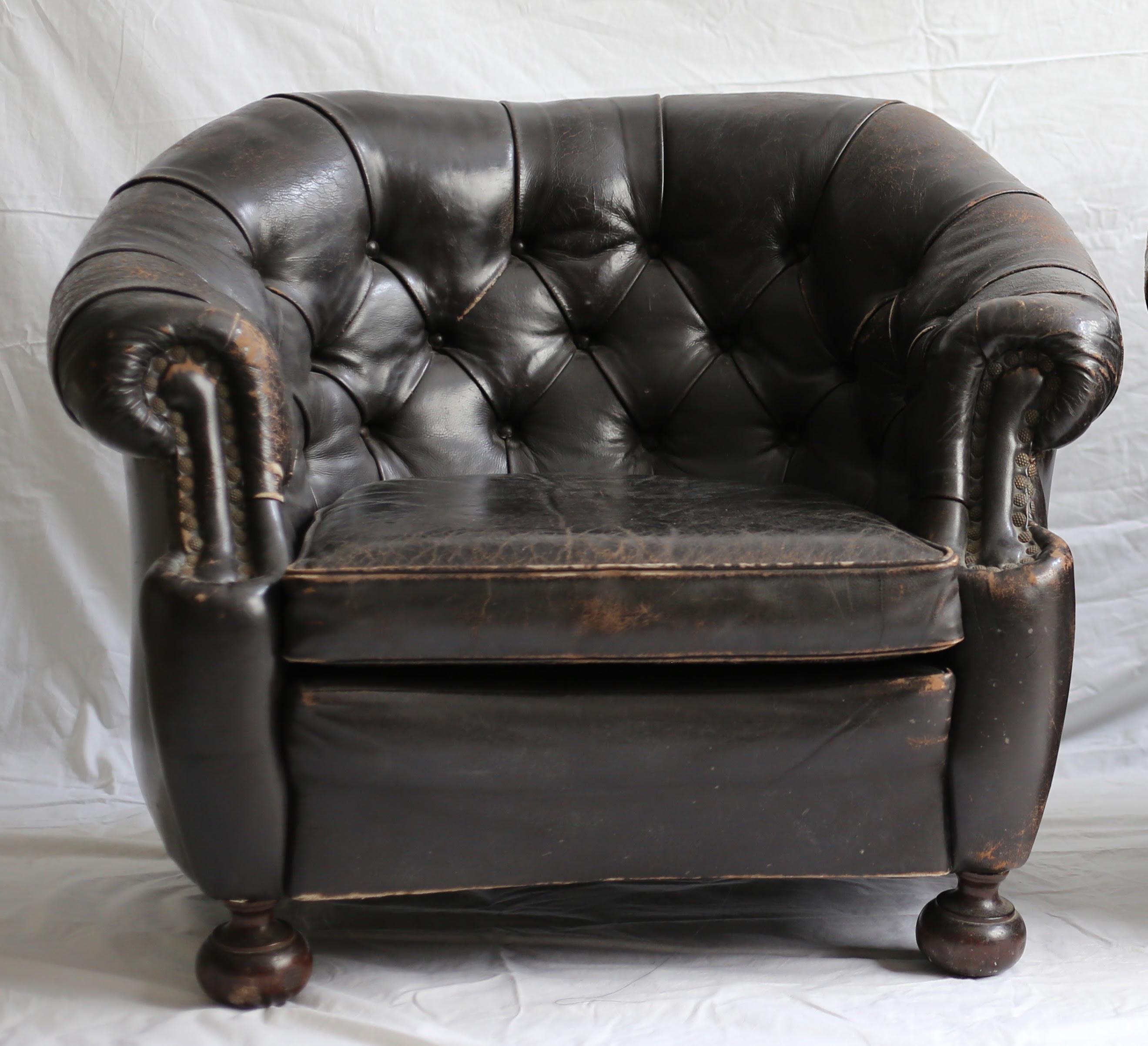 A fantastic pair of vintage Chesterfield button-tufted leather club chairs with lots of character from authentic patina and wear. Upholstered in very dark brown leather with nailhead detailing at the arms and turned wood bun feet.
