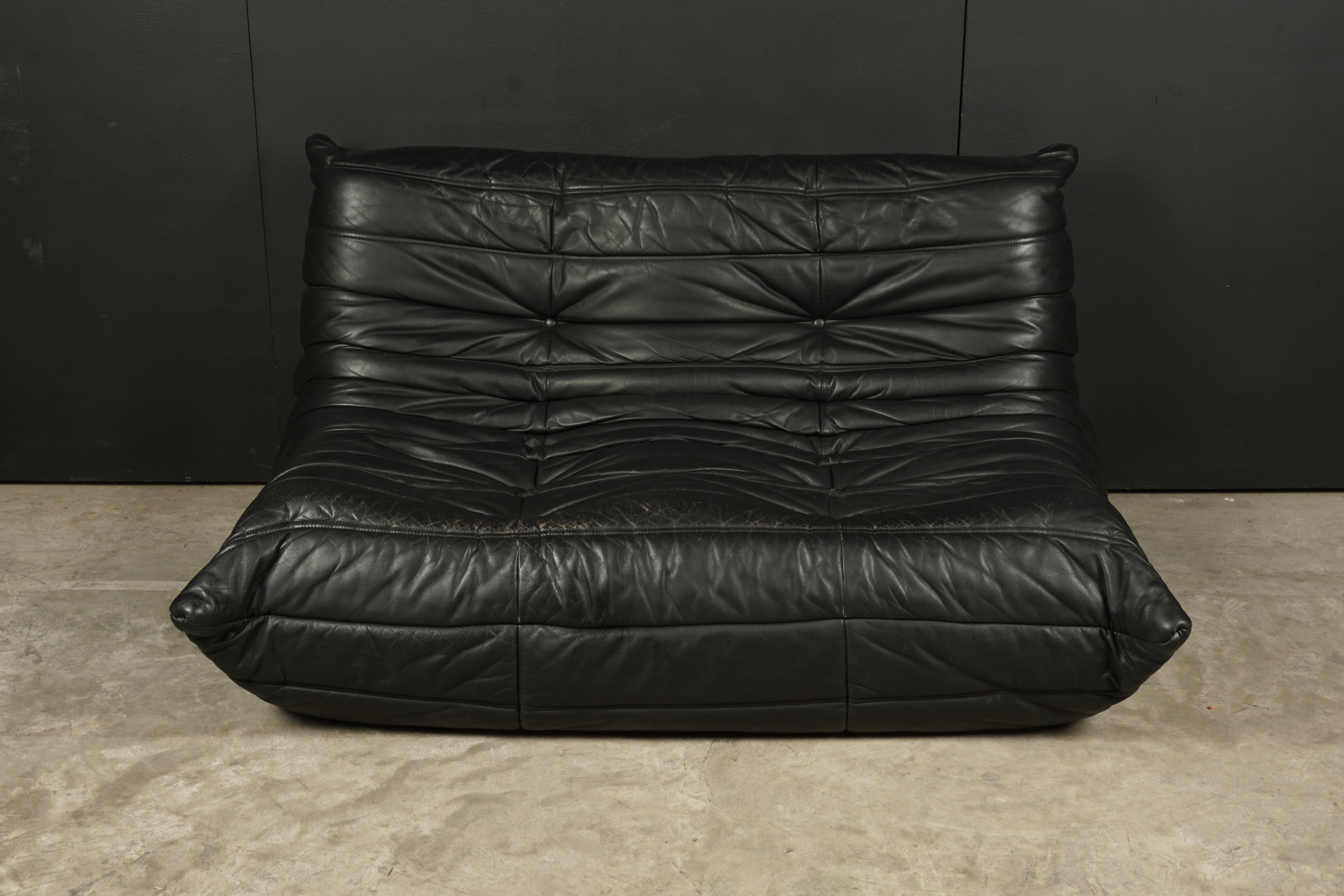 Vintage leather two-seat sofa, model Togo, by Michel Ducaroy for Ligne Roset, France. Original black leather upholstery with original label.