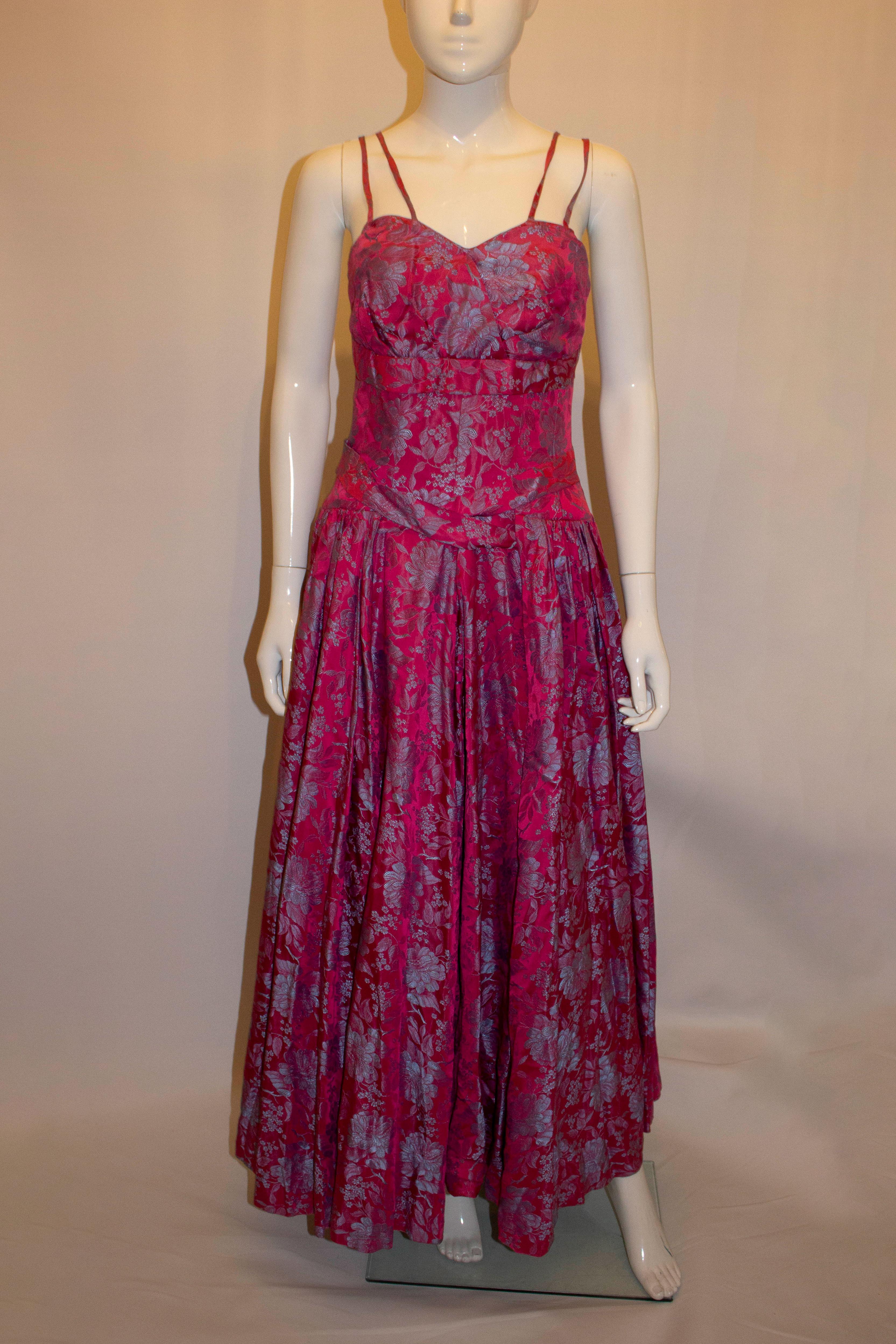 A headturning vintage party /evening dress by Lee Delman. In rose pink with a sky blue background., the dress has a cross over front , full skirt with netting , a central back zip and thin straps. Measurements: Bust 34'', waist 28'', length 56''
