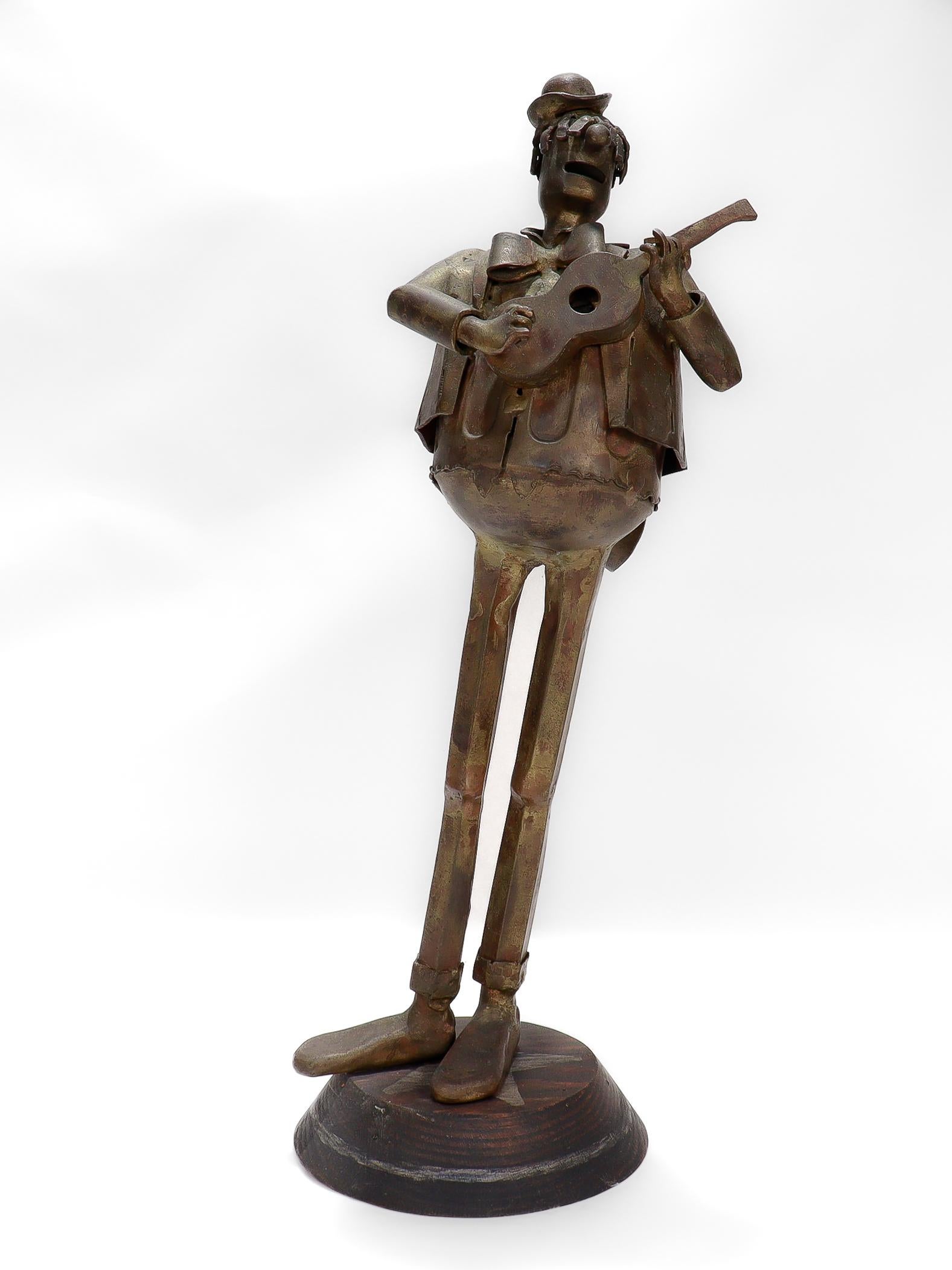 Une belle sculpture figurative vintage en bois et bronze signée.

Par Leo Jensen.

Sous la forme d'un homme portant un costume et un chapeau melon et jouant de la guitare ou du ukulélé.

Signé à la base du socle.

Tout simplement une magnifique