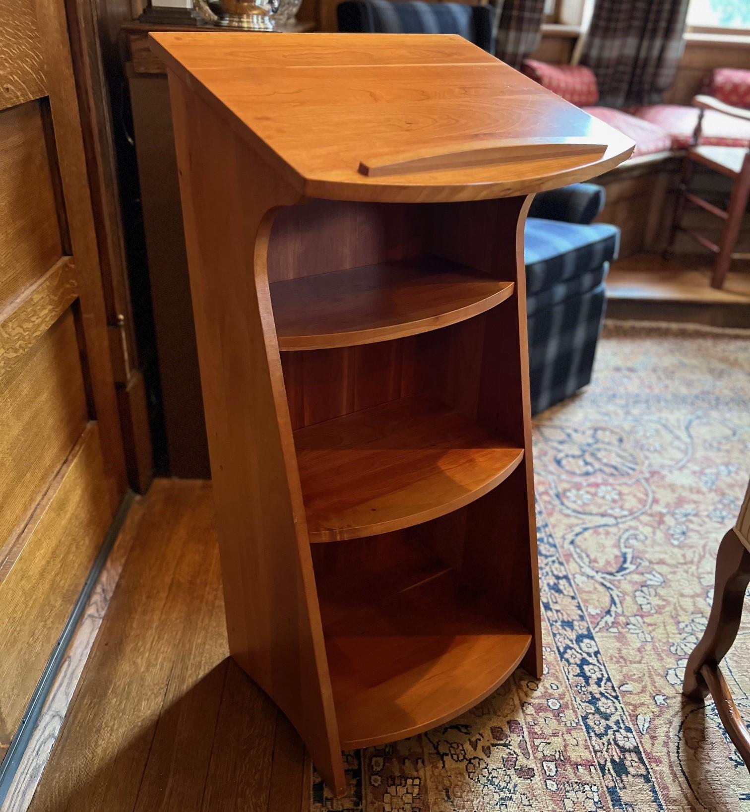 Late 20th C. a Levenger cherry wood library stand of a clean, minimalist design. The stand features a slanted top for use as a lectern, for reading or displaying books, music, or other items. The slanted surface also has a small lip at the edge to