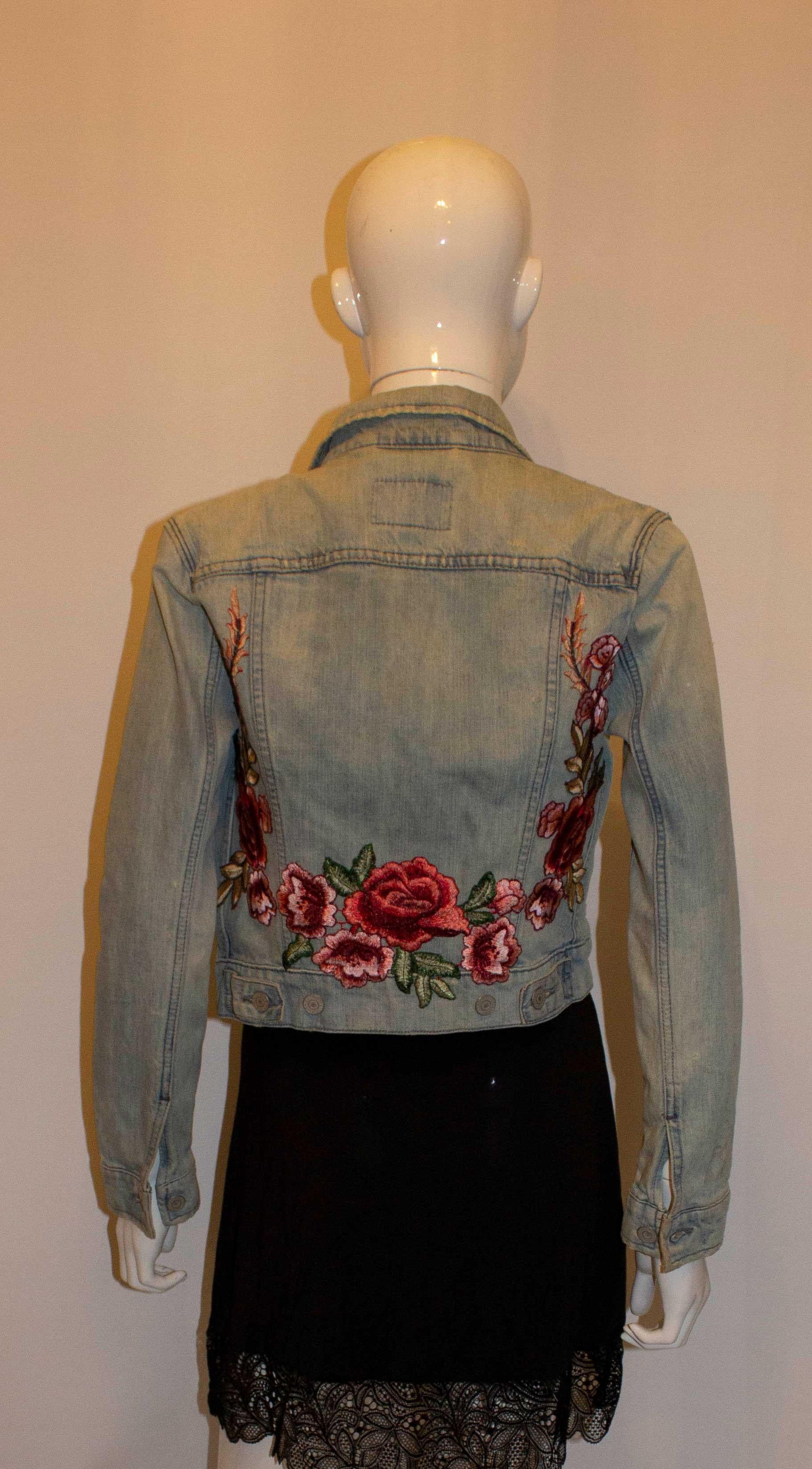 A headturning vintage  denim jacket by Levis. The jacket has a button front and cuffs, with wonderful red and pink floral embroidery on the back. It has two patch pockets at breast leval and two pockets at the front at lower leval.
Size P /S