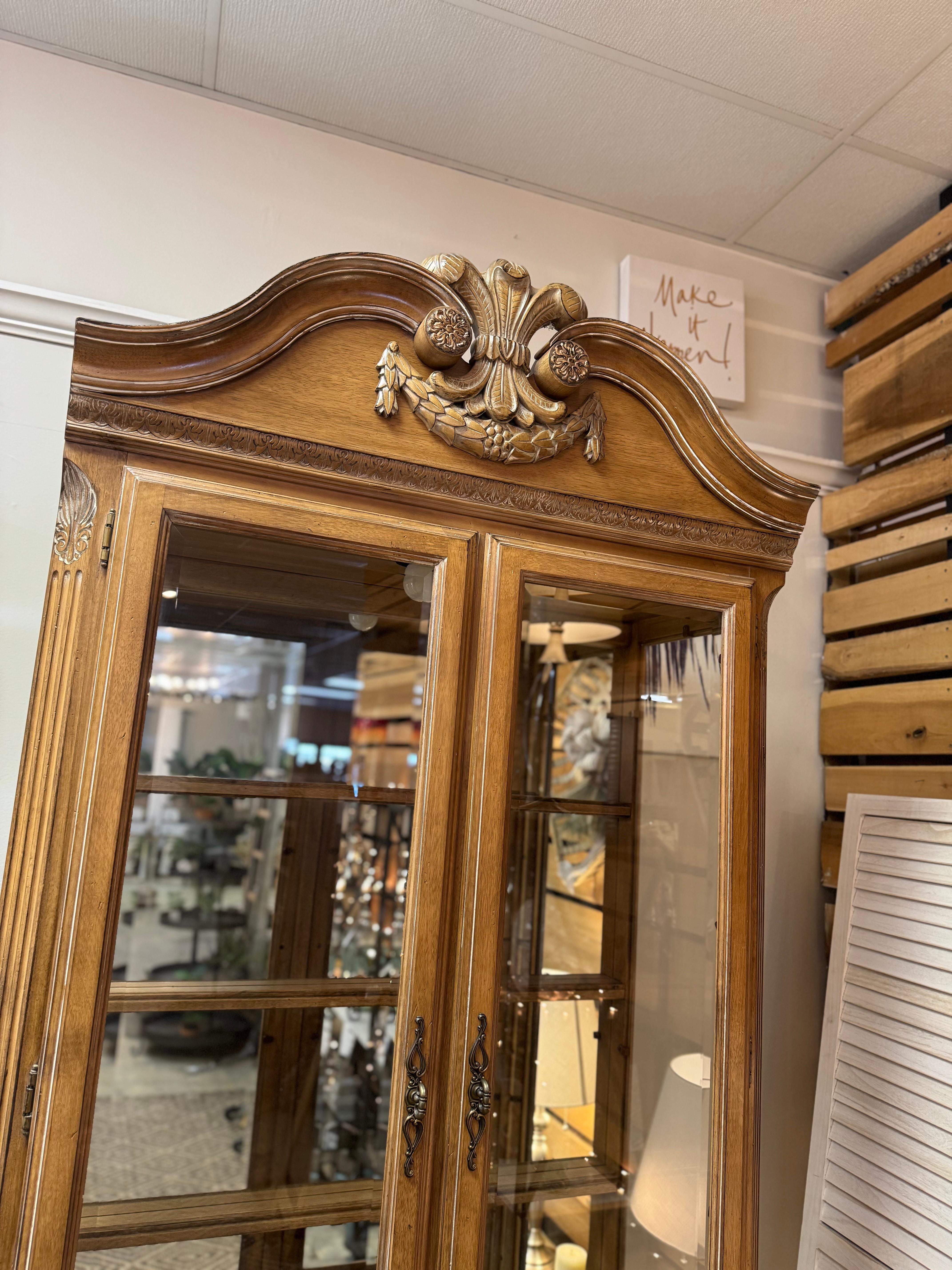 Armadio per porcellane in stile tradizionale Lexington con finitura chiara. Ci sono tre ripiani in vetro con retro a specchio, che riflettono l'ambiente circostante.  nella foto  con due cassetti sotto il cassetto superiore, foderati e divisi per
