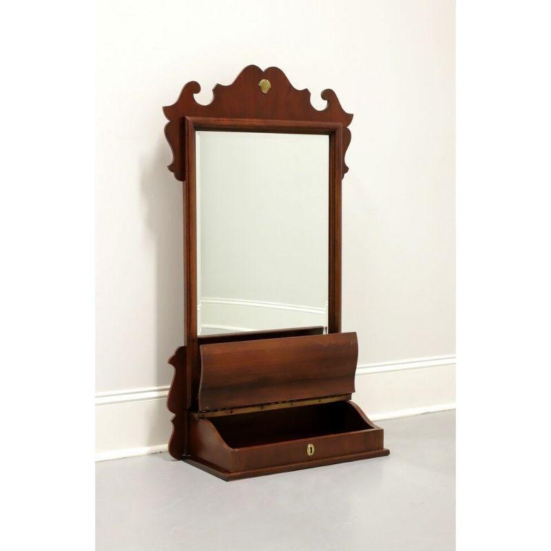 A Chippendale style shaving mirror for dresser or vanity top by Lexington Furniture. Beveled mirrored glass, portrait oriented, decoratively carved mahogany frame with gold shell ornamentation. Drawer base for storage with lifting scroll lid and